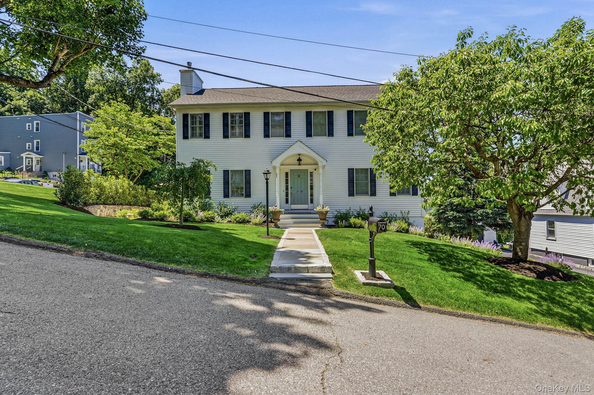 White clapboard exterior with black shutters, a covered entry, and a light blue front door