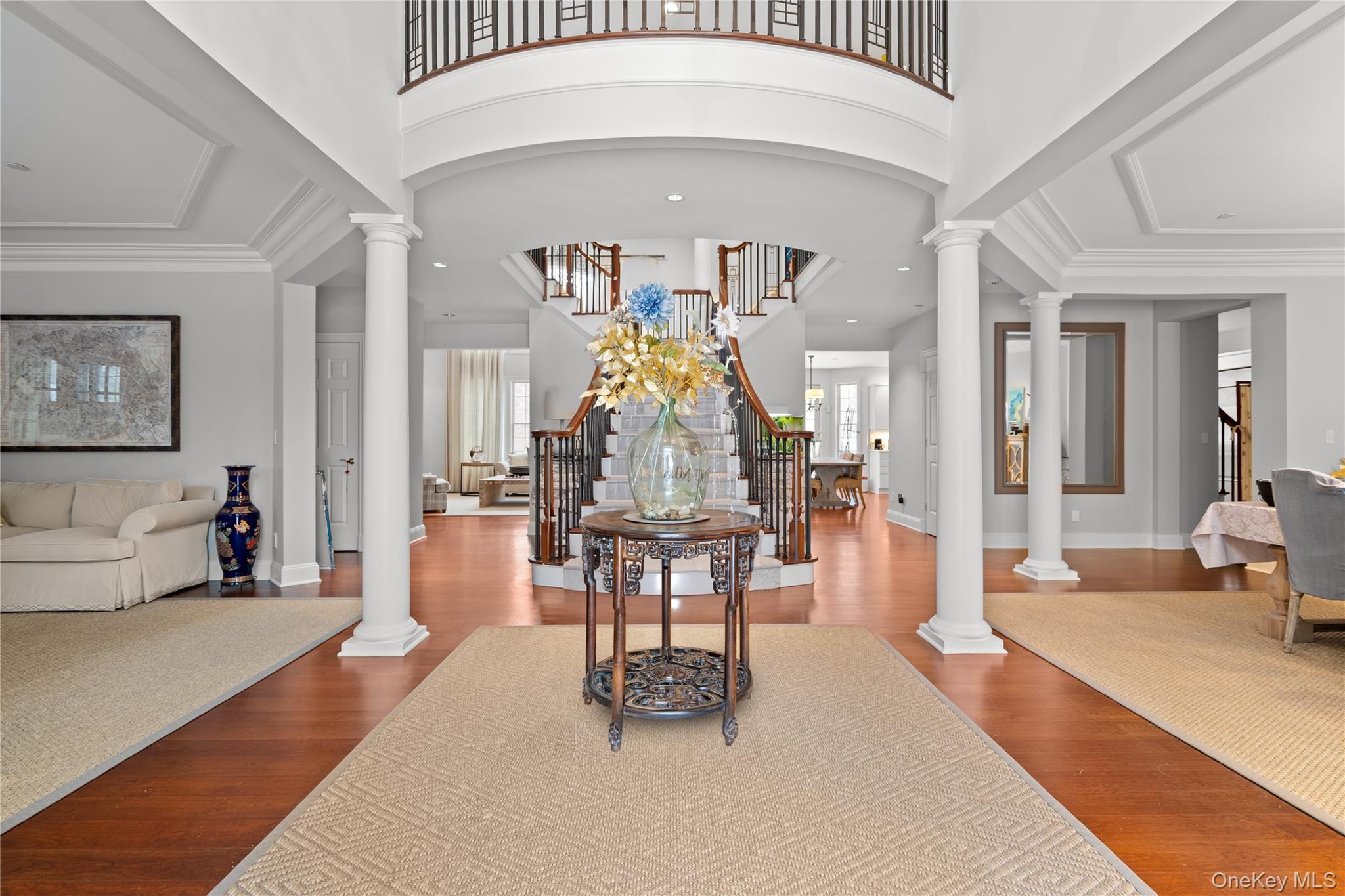 Entryway featuring ornate columns, plenty of natural light, dark wood-style floors, recessed lighting, and a high ceiling