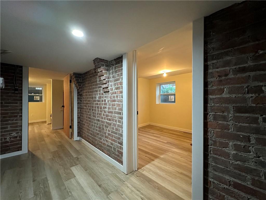 Corridor featuring brick wall and light hardwood / wood-style floors