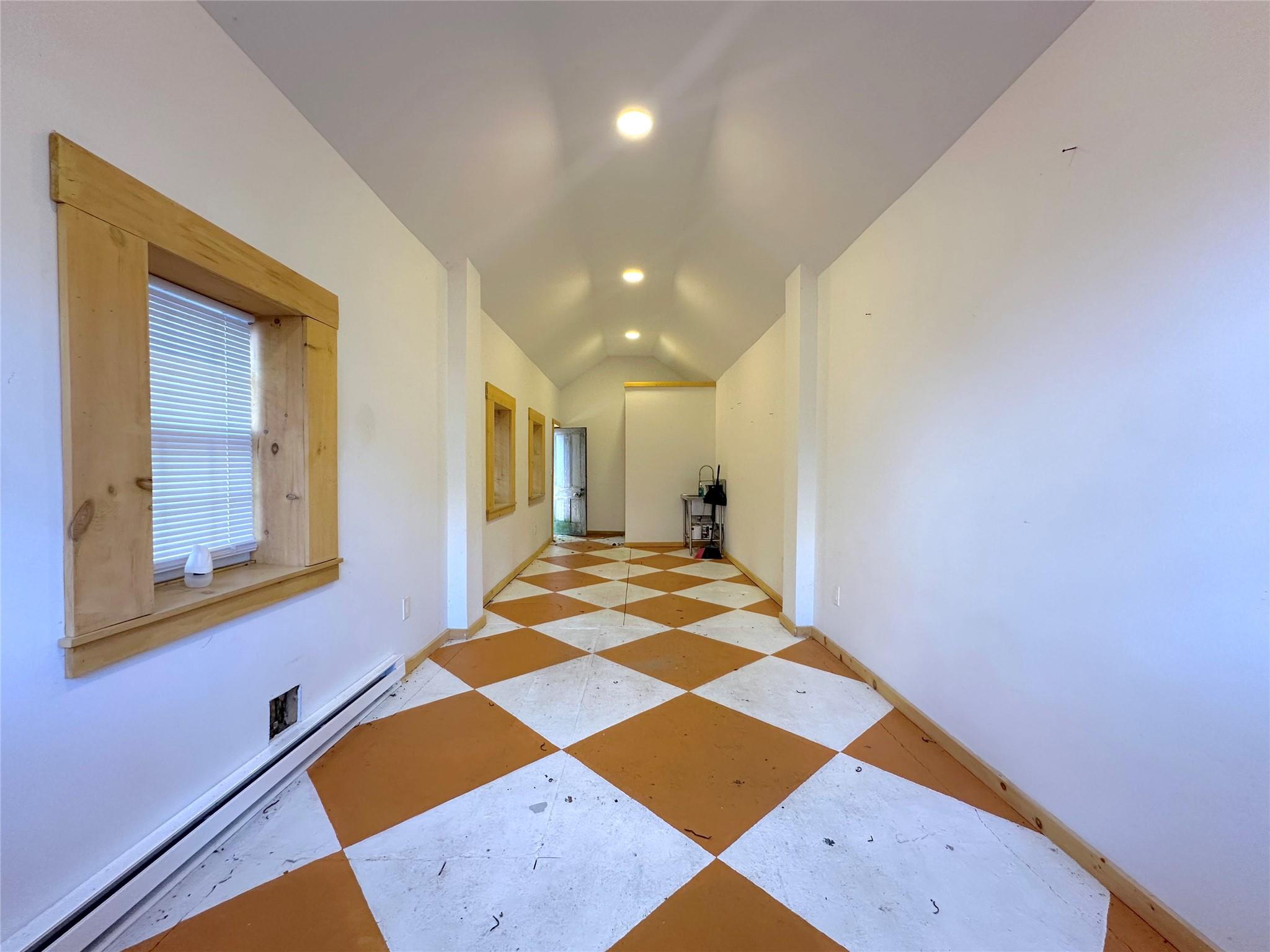 Hall with lofted ceiling and a baseboard heating unit