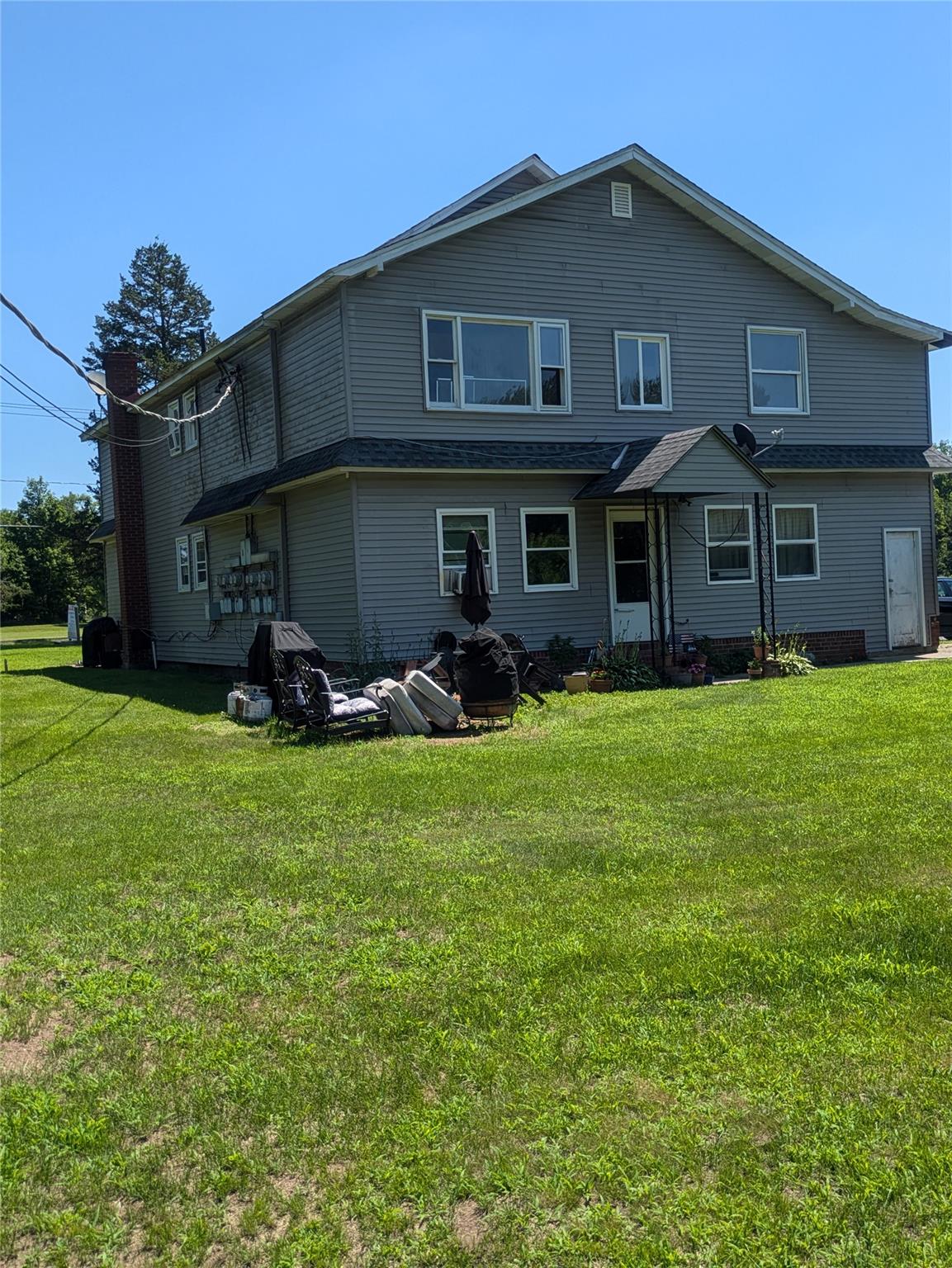 Back of house featuring a lawn and a chimney