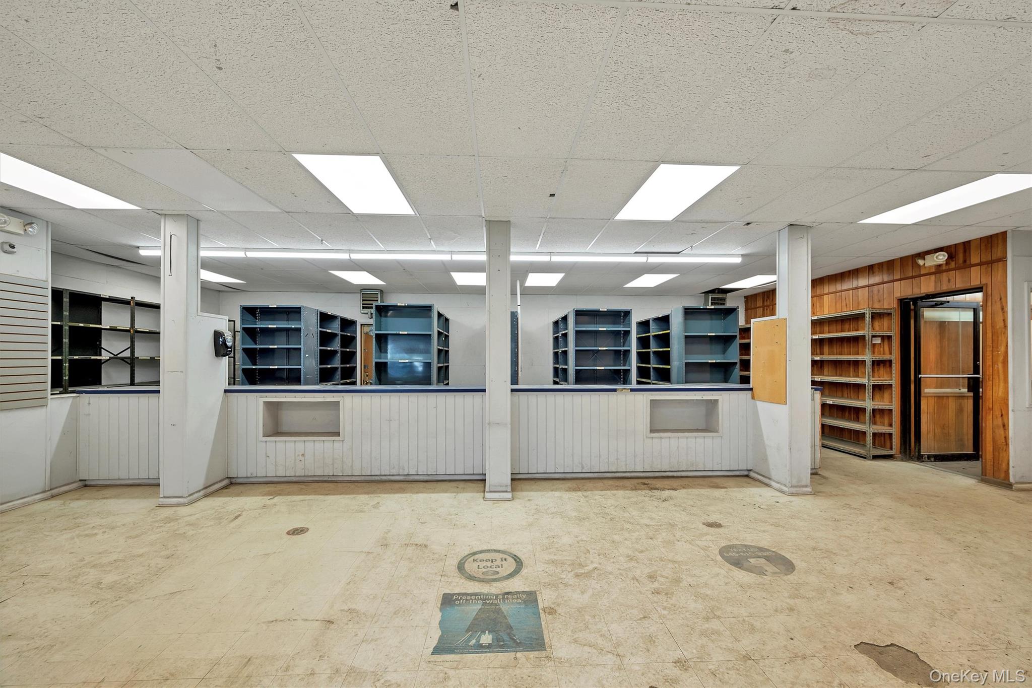 Unfurnished room with a drop ceiling and wood walls