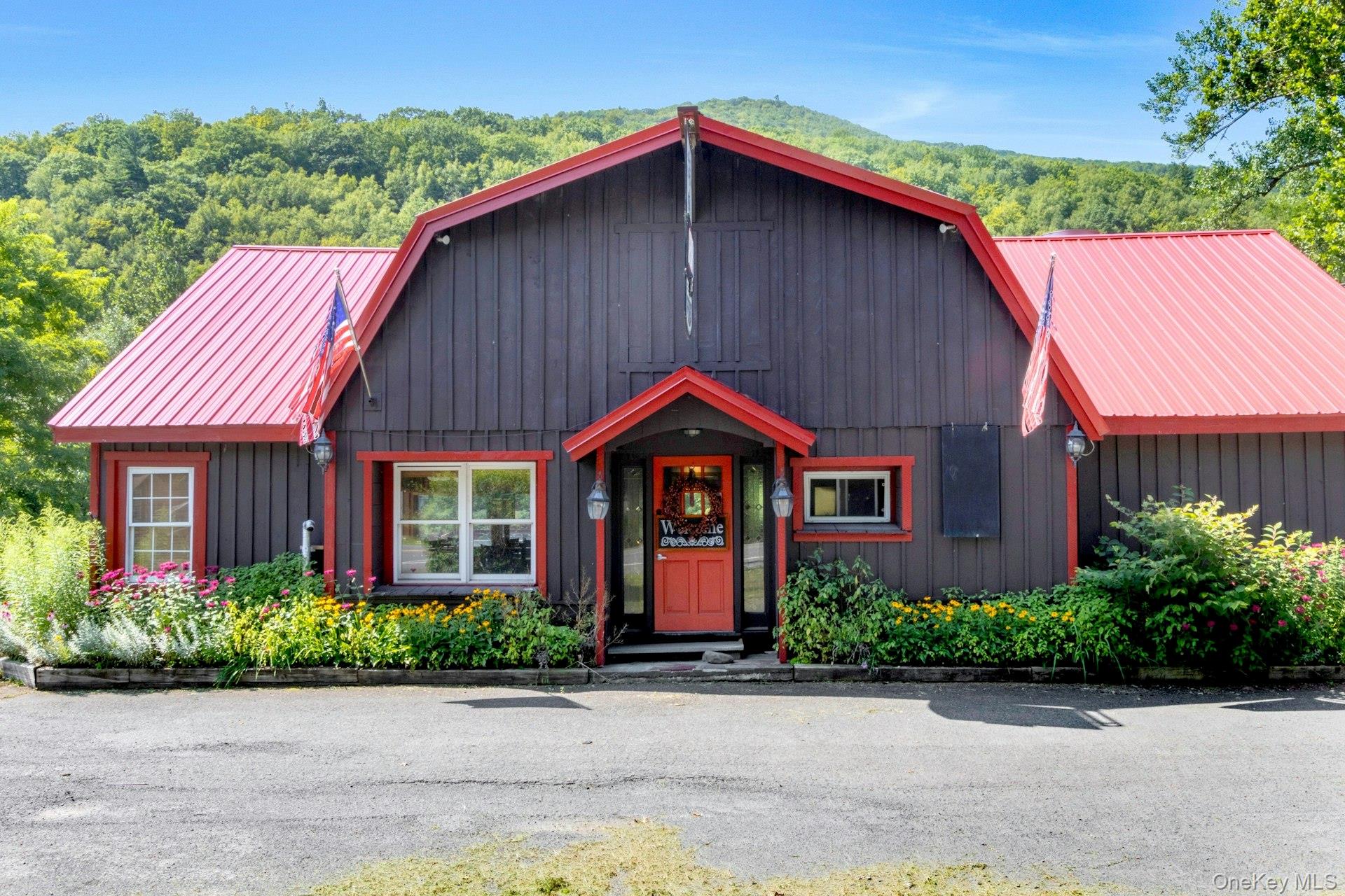 Chalet / cabin featuring a gambrel roof, a metal roof, and a view of trees