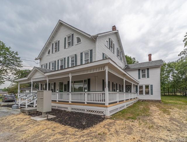 View of front of property featuring covered porch and a chimney