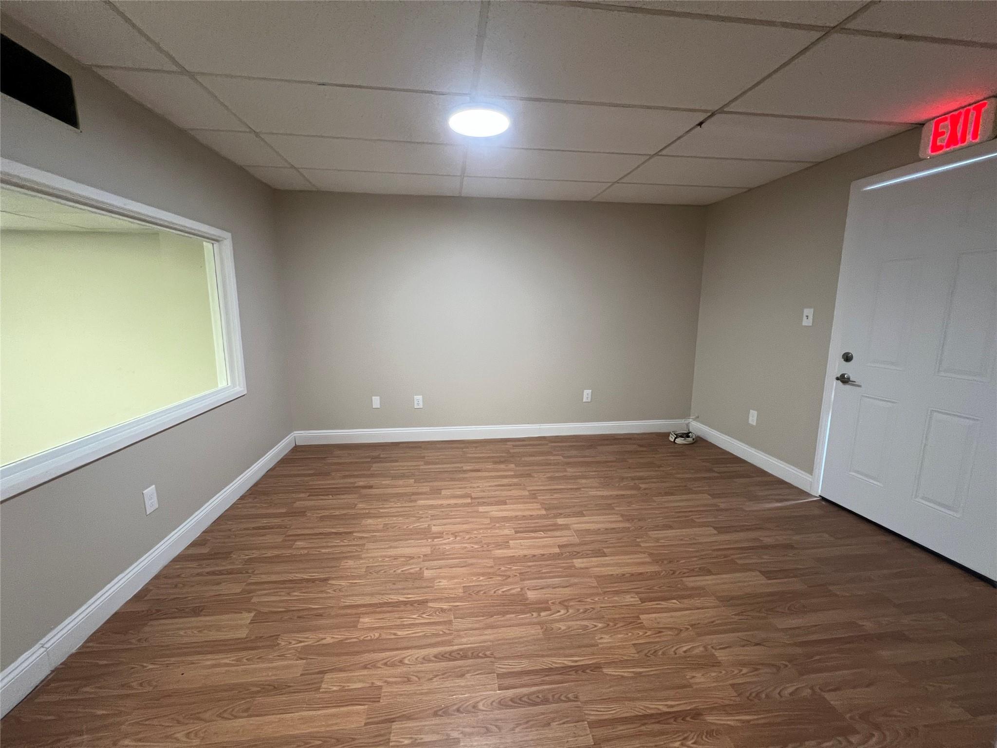 Finished basement featuring wood finished floors, baseboards, and a paneled ceiling