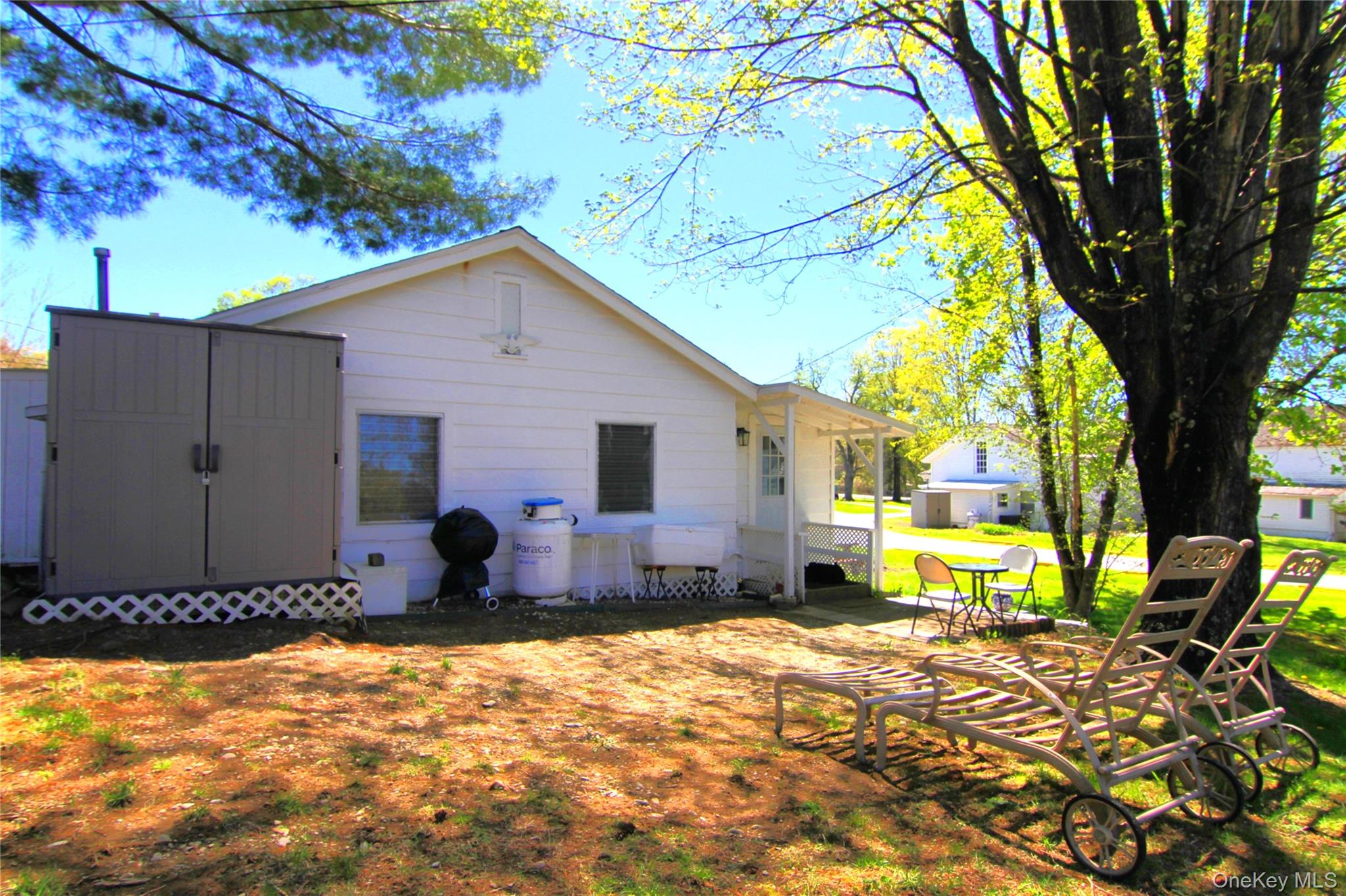 Rear view of property with an outdoor structure, a lawn, a shed, and a patio