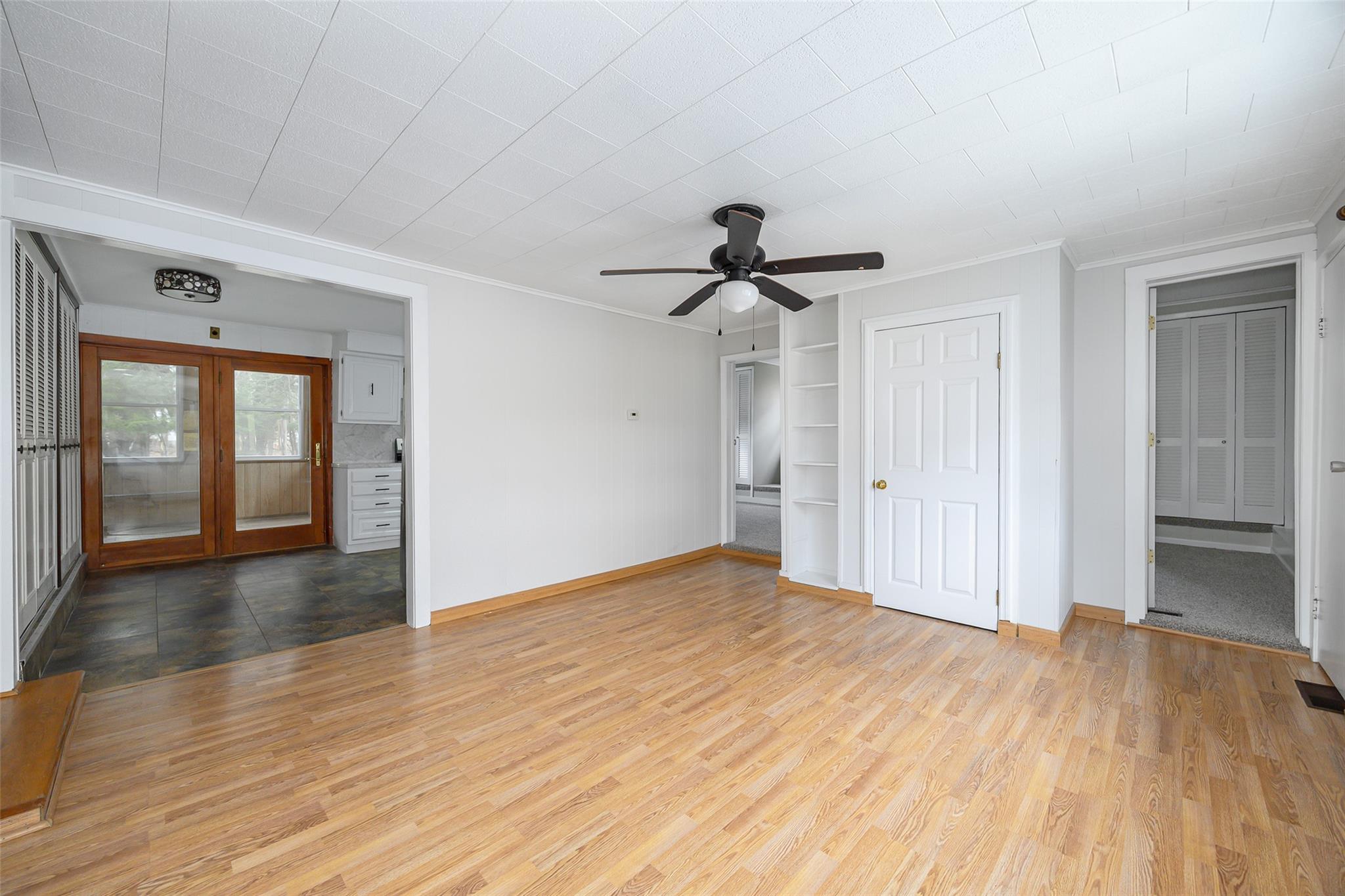 Unfurnished living room featuring crown molding, ceiling fan, and wood finished floors
