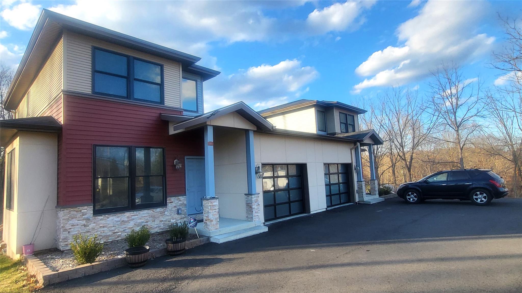 Modern home featuring stone siding, driveway, and an attached garage