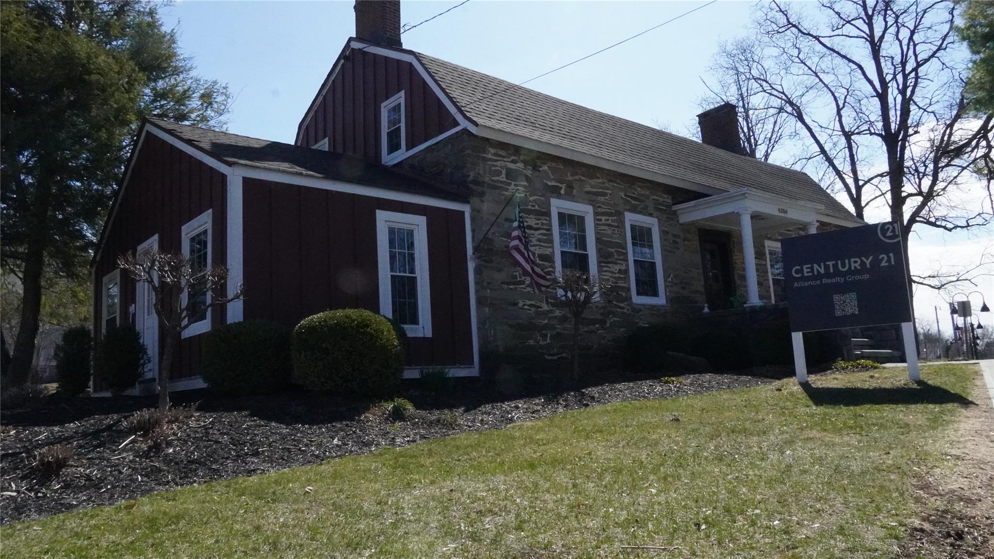 View of property exterior featuring stone siding, board and batten siding, a yard, and a chimney
