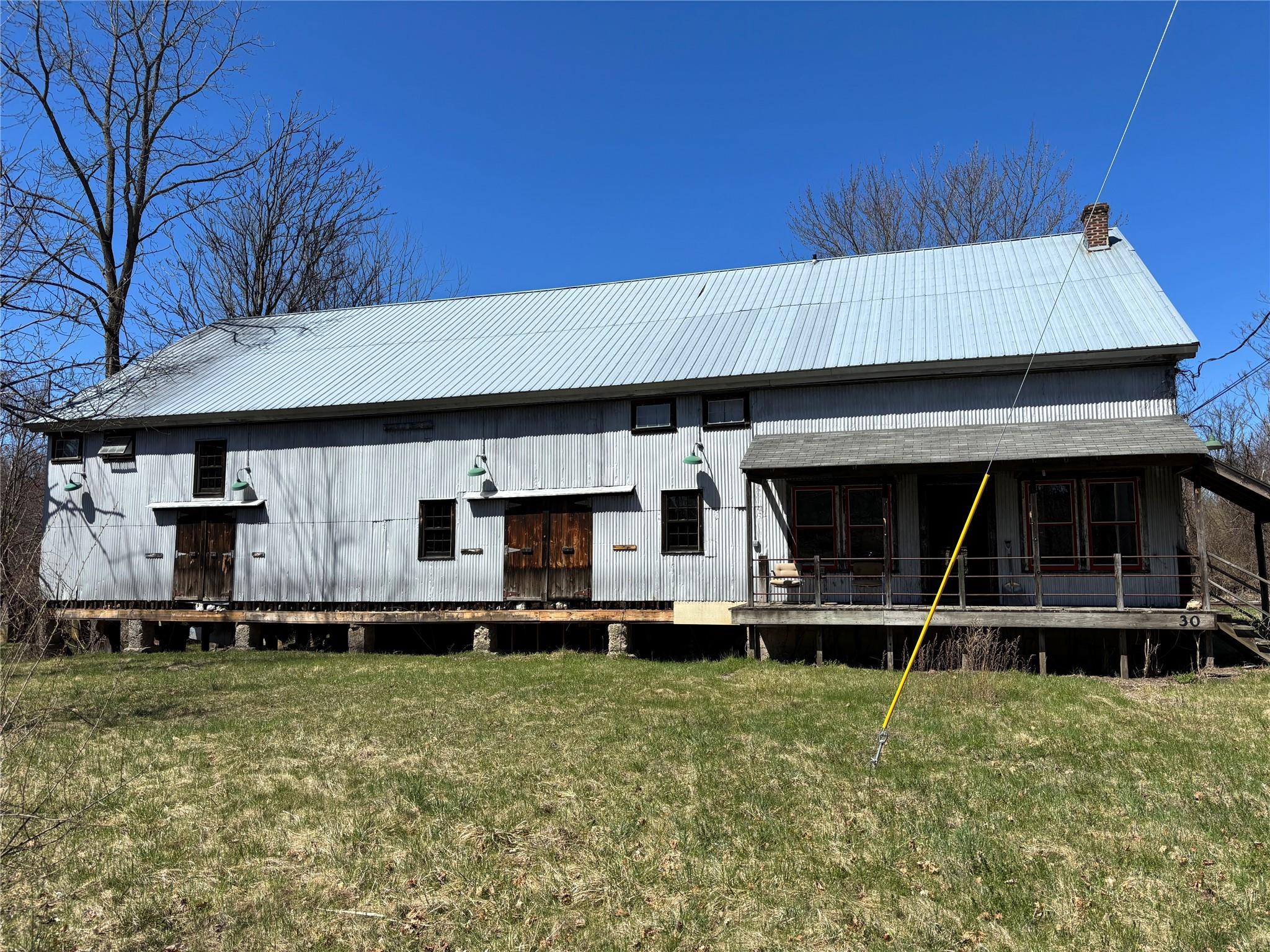 Back of property featuring metal roof, a lawn, and a chimney