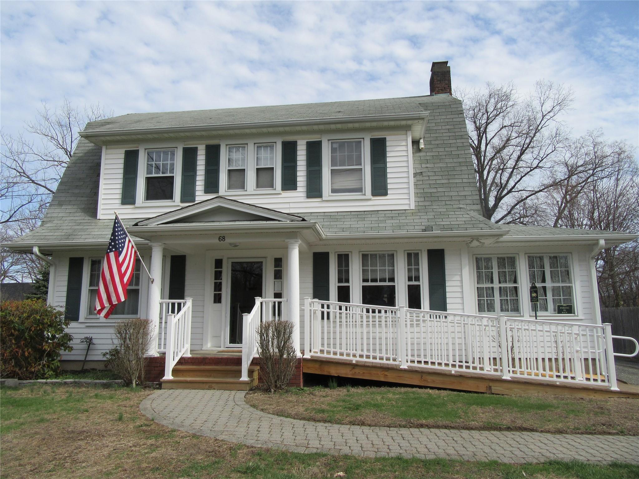 View of front of house with roof with shingles, covered porch, and a chimney