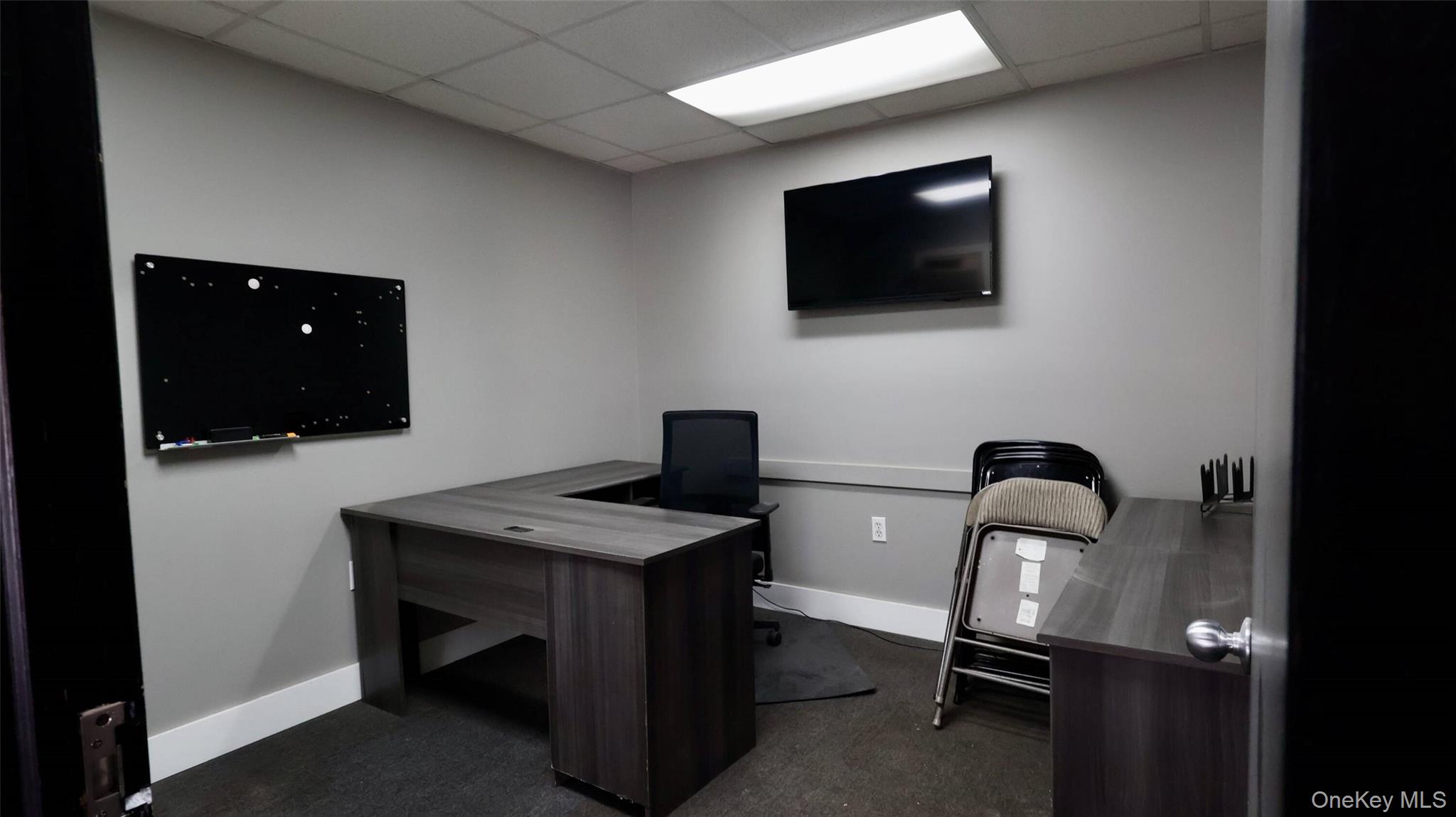 Office with dark carpet, baseboards, and a drop ceiling