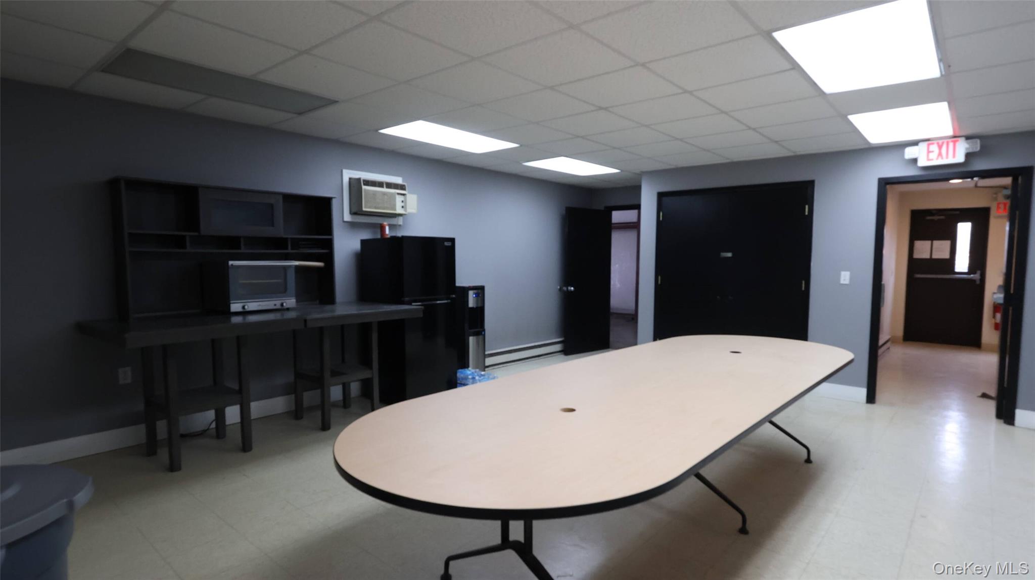 Game room featuring a wall unit AC, a baseboard heating unit, a drop ceiling, and light floors