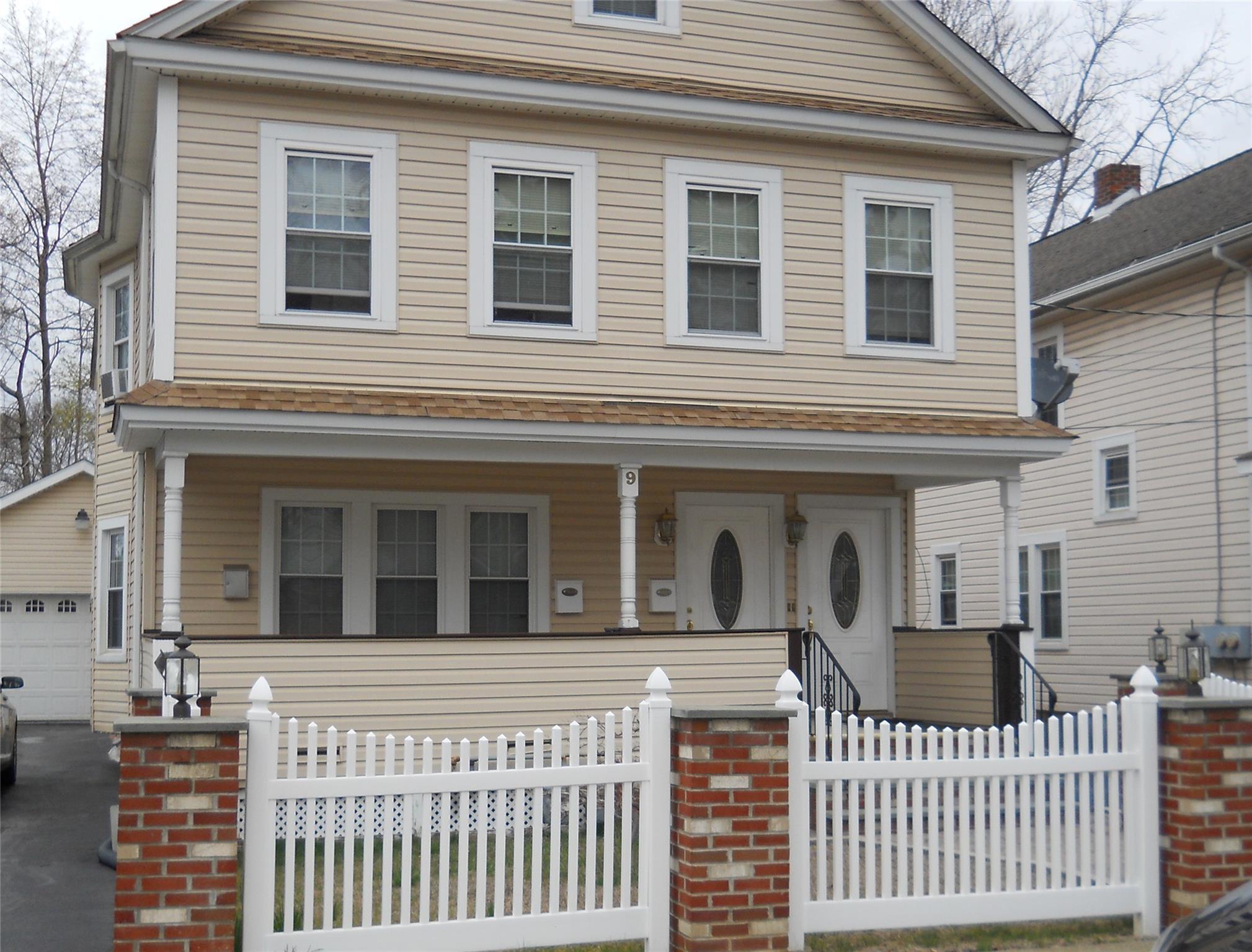 View of front of house with fence, covered porch, and a garage