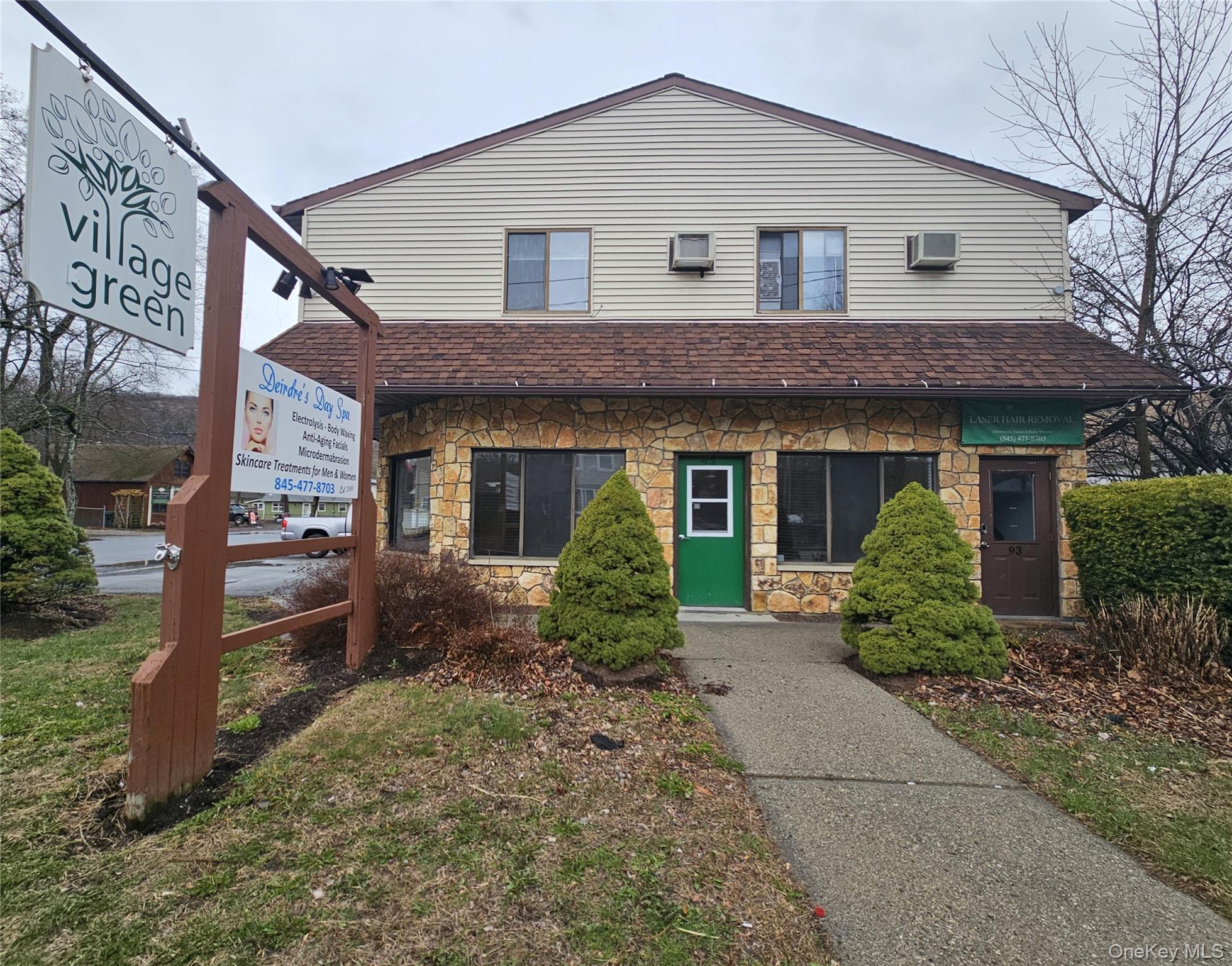 View of front of property with stone siding and a wall mounted AC