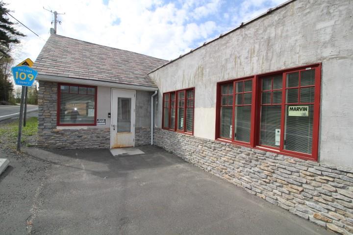 Entrance to property with a shingled roof and stone siding