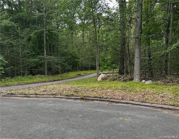 View of asphalt street with curbs and a view of trees