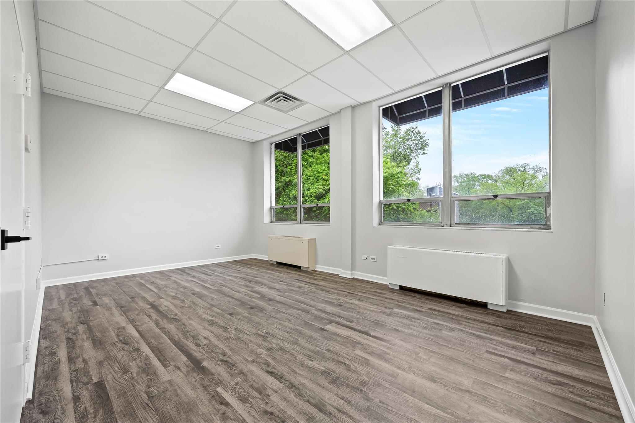Empty room featuring radiator heating unit, wood finished floors, and baseboards