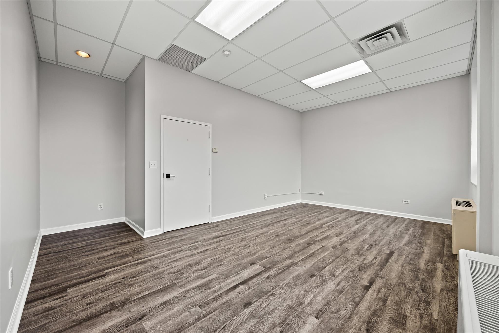 Spare room with dark wood-style floors, baseboards, a drop ceiling, and recessed lighting