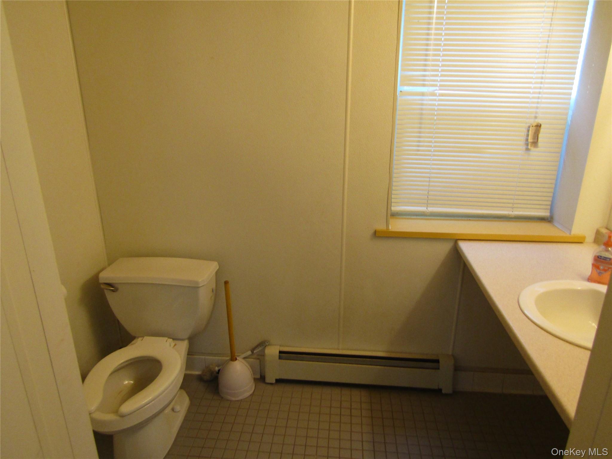 Bathroom featuring tile patterned floors, toilet, a baseboard heating unit, and sink