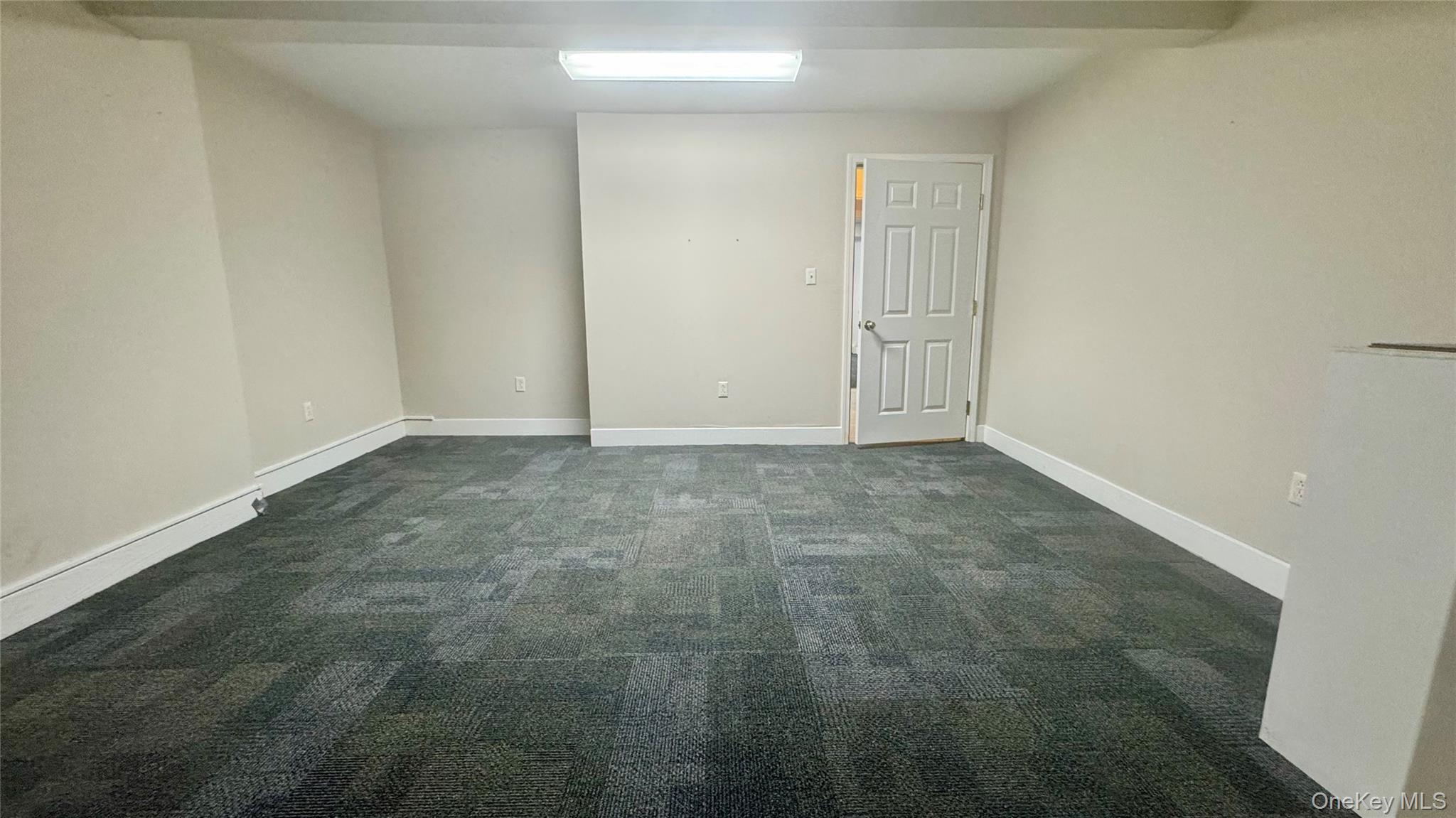 Unfurnished room with dark colored carpet and baseboards