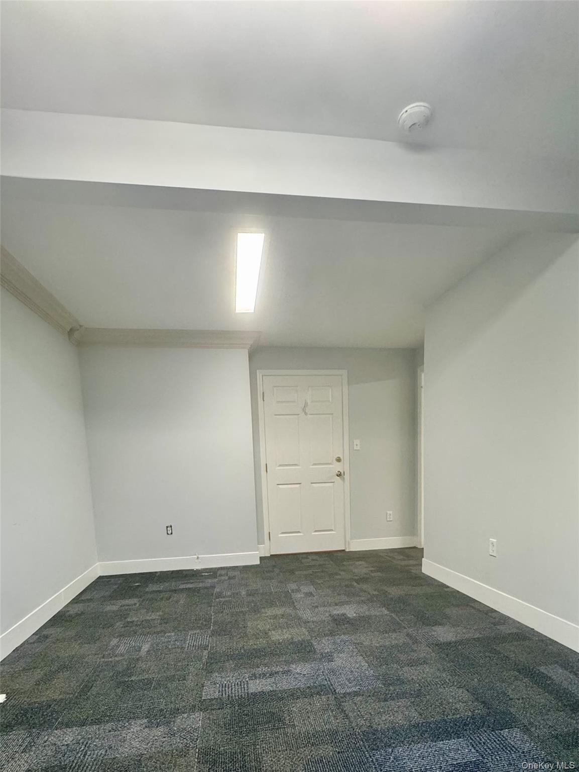 Below grade area featuring dark carpet and baseboards