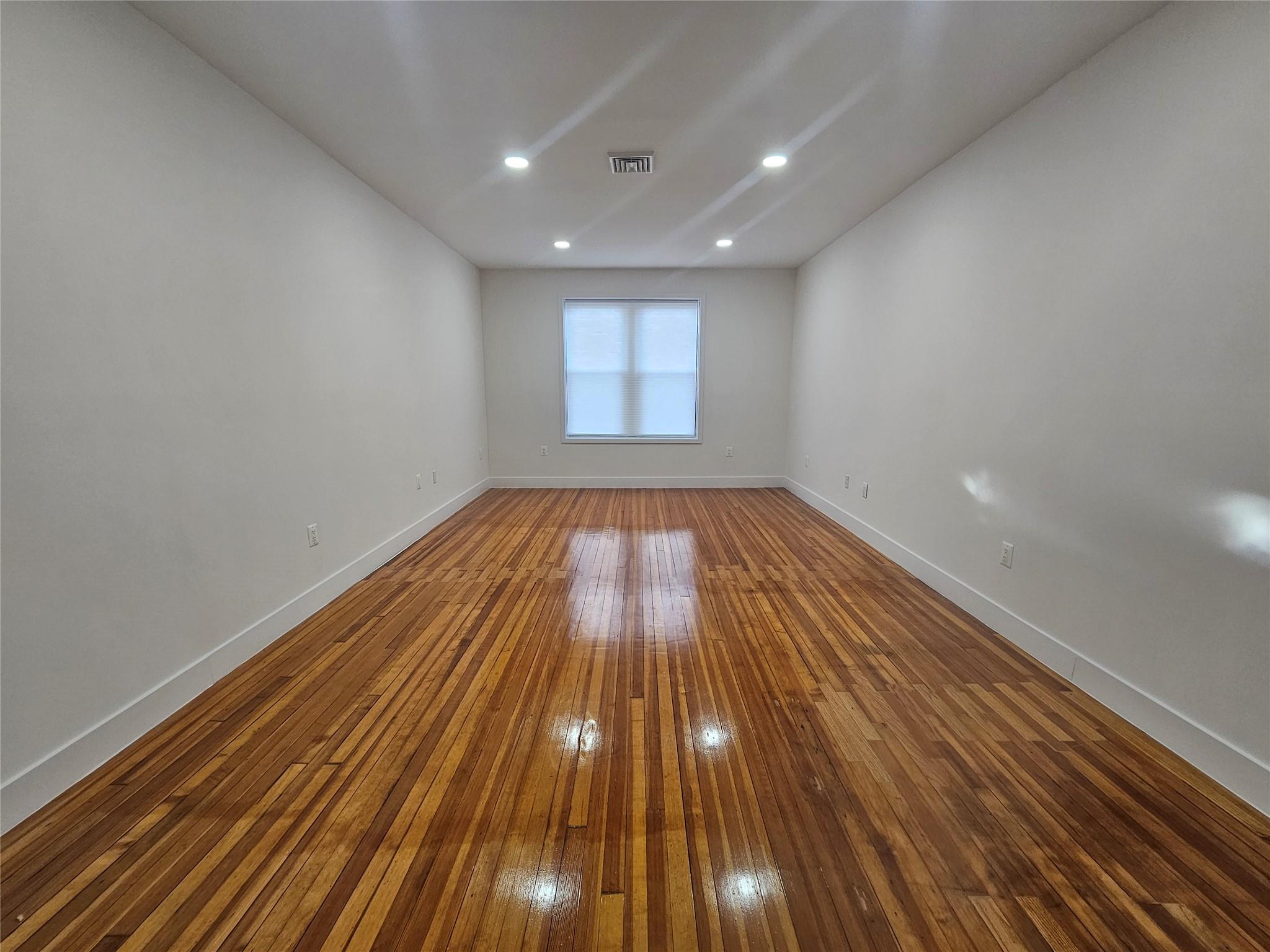 Empty room featuring hardwood / wood-style floors, baseboards, and recessed lighting