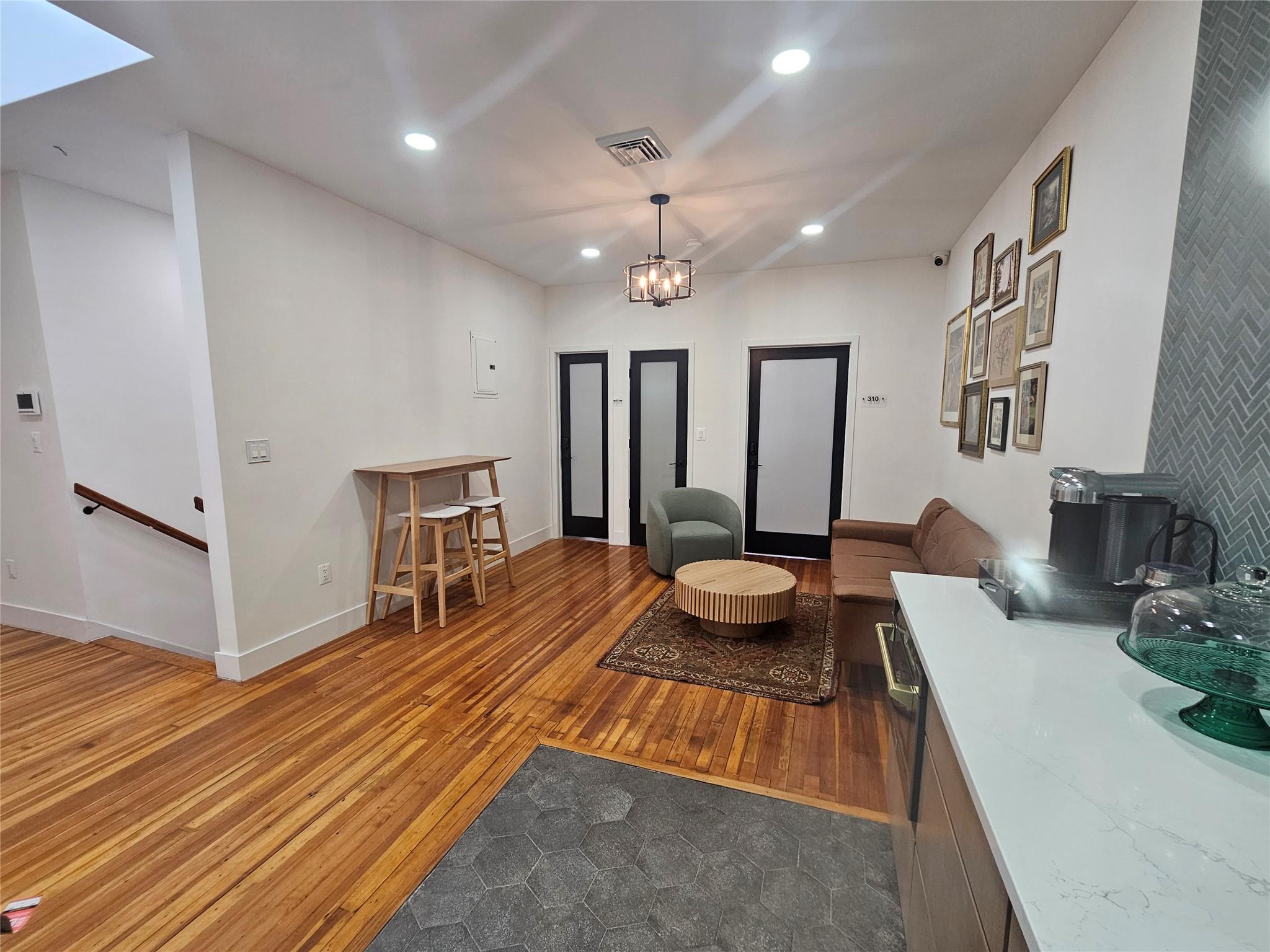 Living room with recessed lighting, hardwood / wood-style flooring, baseboards, and a chandelier