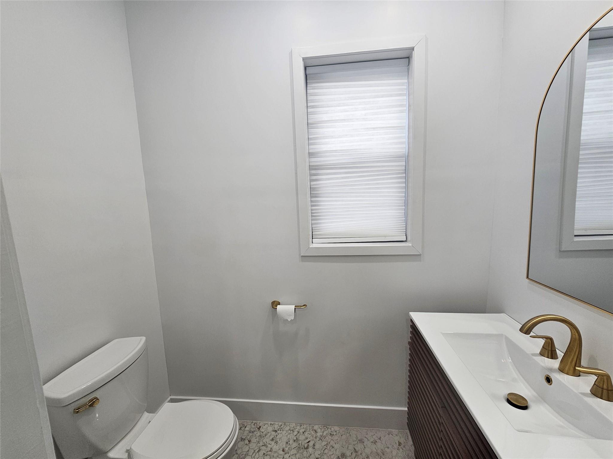 Half bath featuring toilet, baseboards, and vanity