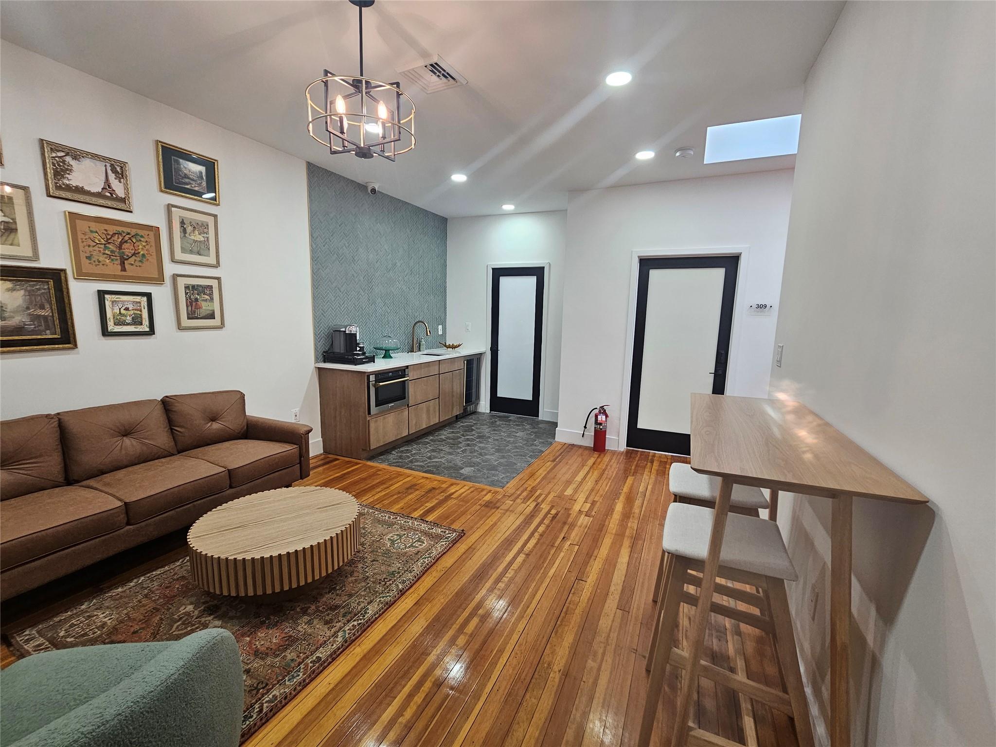 Living area with dark wood-style floors, recessed lighting, a chandelier, a skylight, and baseboards