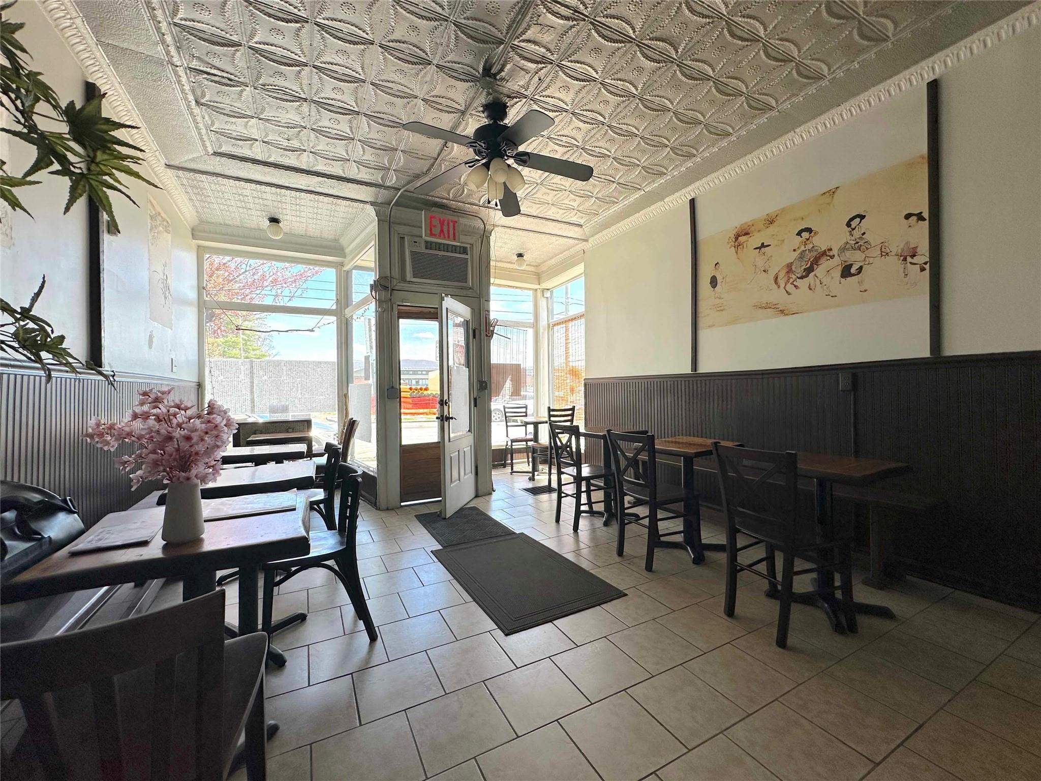 Sunroom / solarium with outdoor dining area, ceiling fan, a wainscoted wall, an ornate ceiling, and crown molding