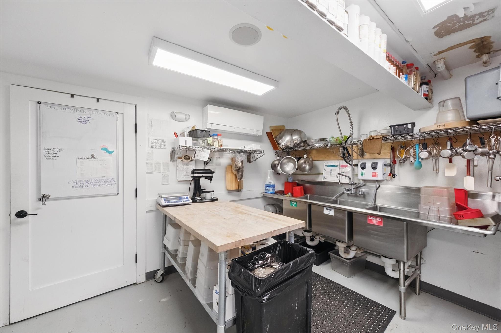 Kitchen featuring finished concrete floors, a wall mounted air conditioner, open shelves, and white cabinetry