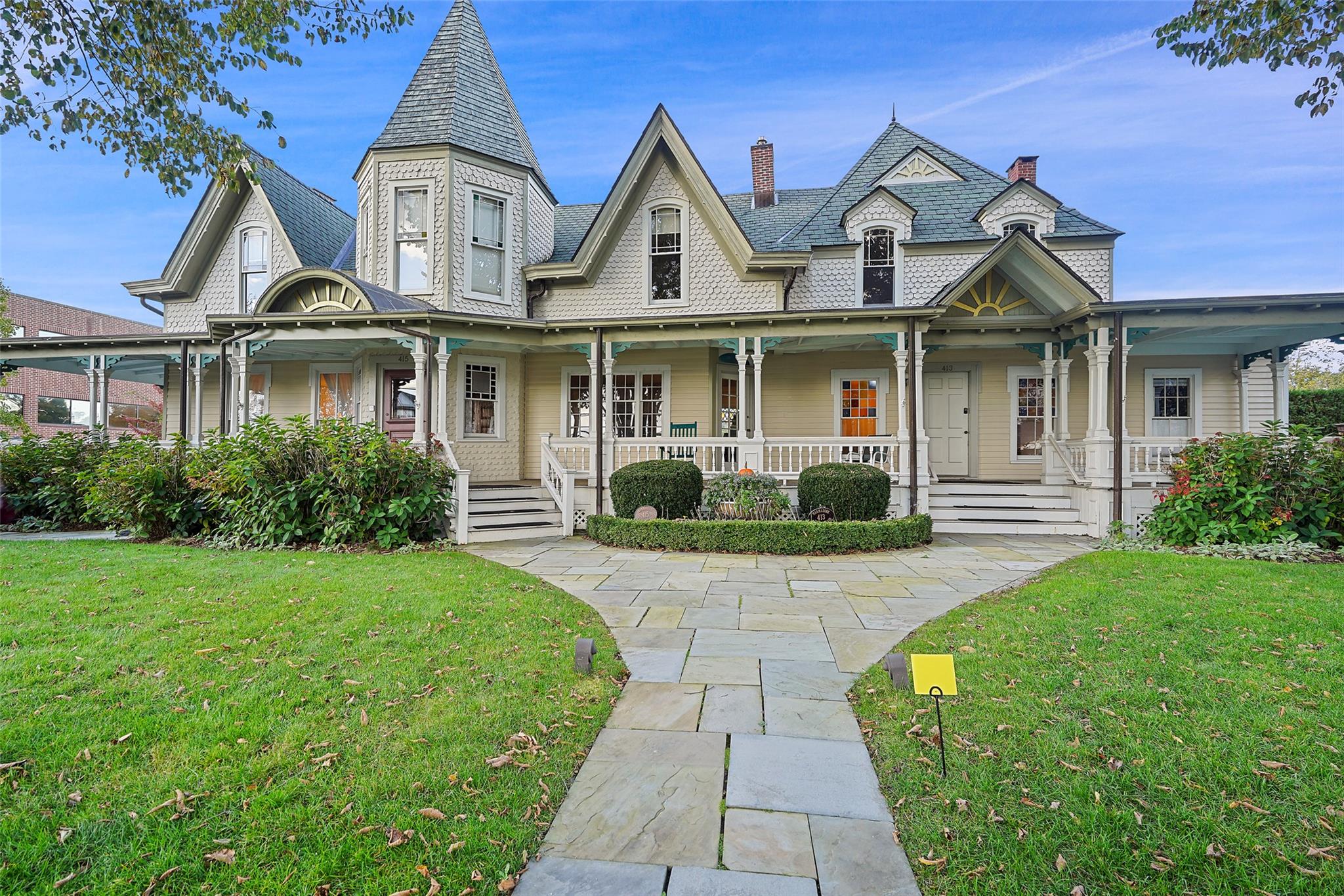 Victorian home with a front yard, a chimney, and covered porch