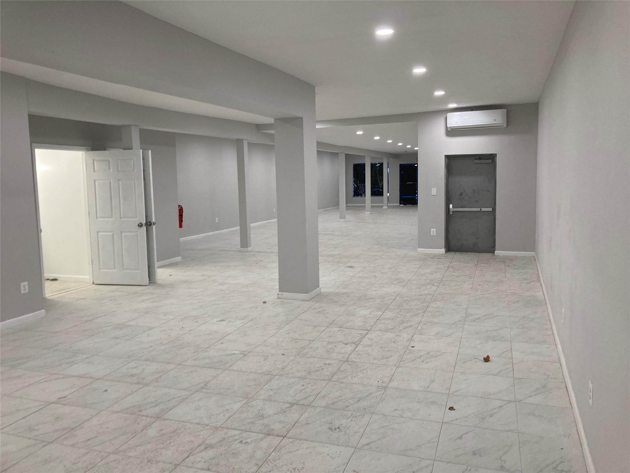 Finished below grade area featuring an AC wall unit, baseboards, and recessed lighting