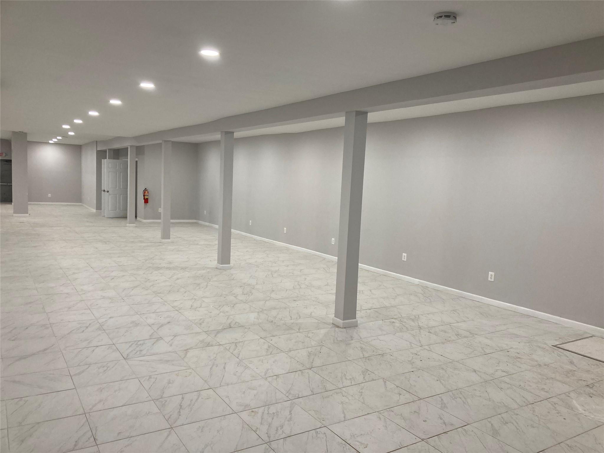 Finished below grade area with recessed lighting, baseboards, and light marble finish floors