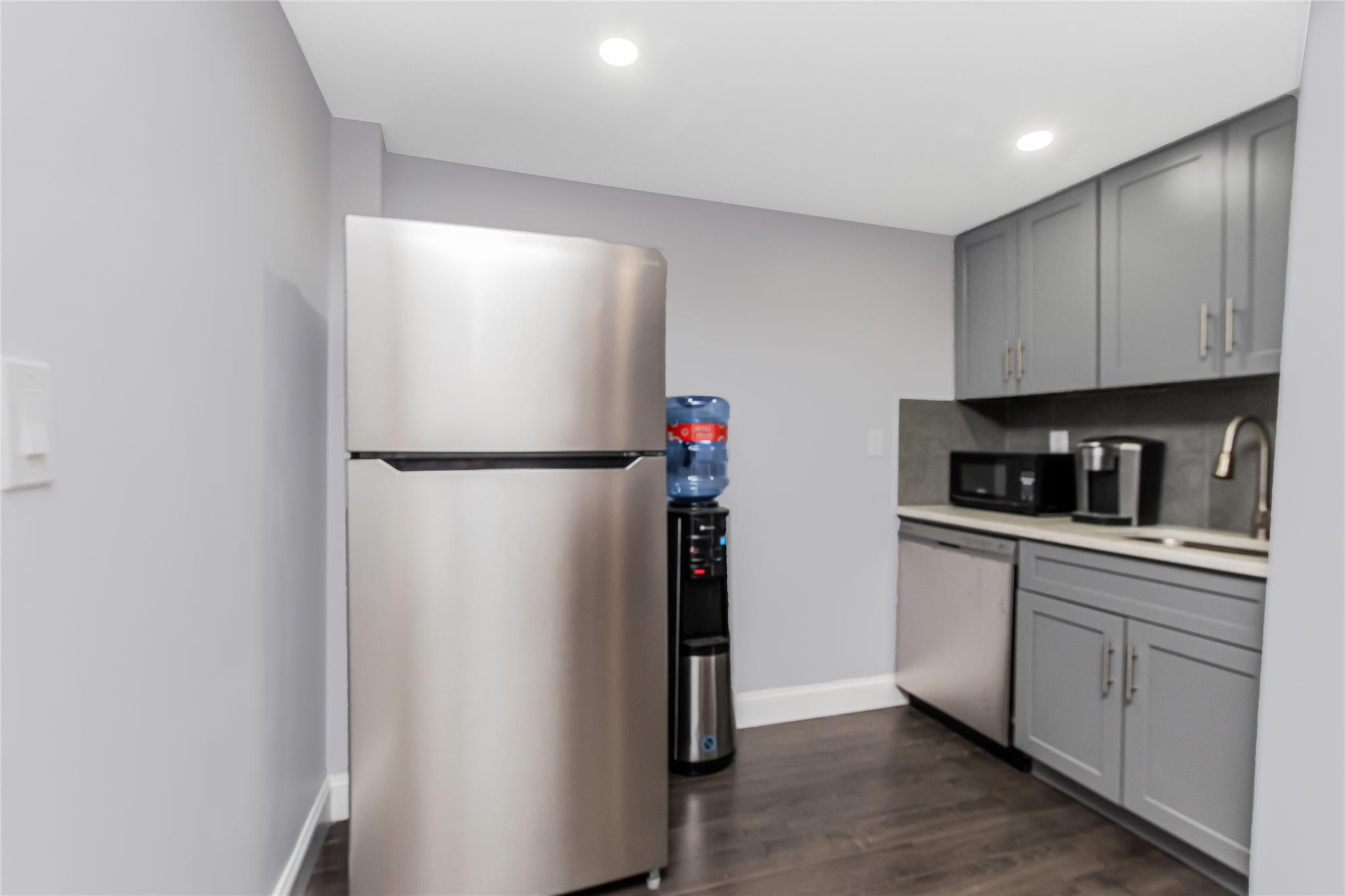 Kitchen featuring stainless steel appliances, gray cabinets, a sink, light countertops, and recessed lighting