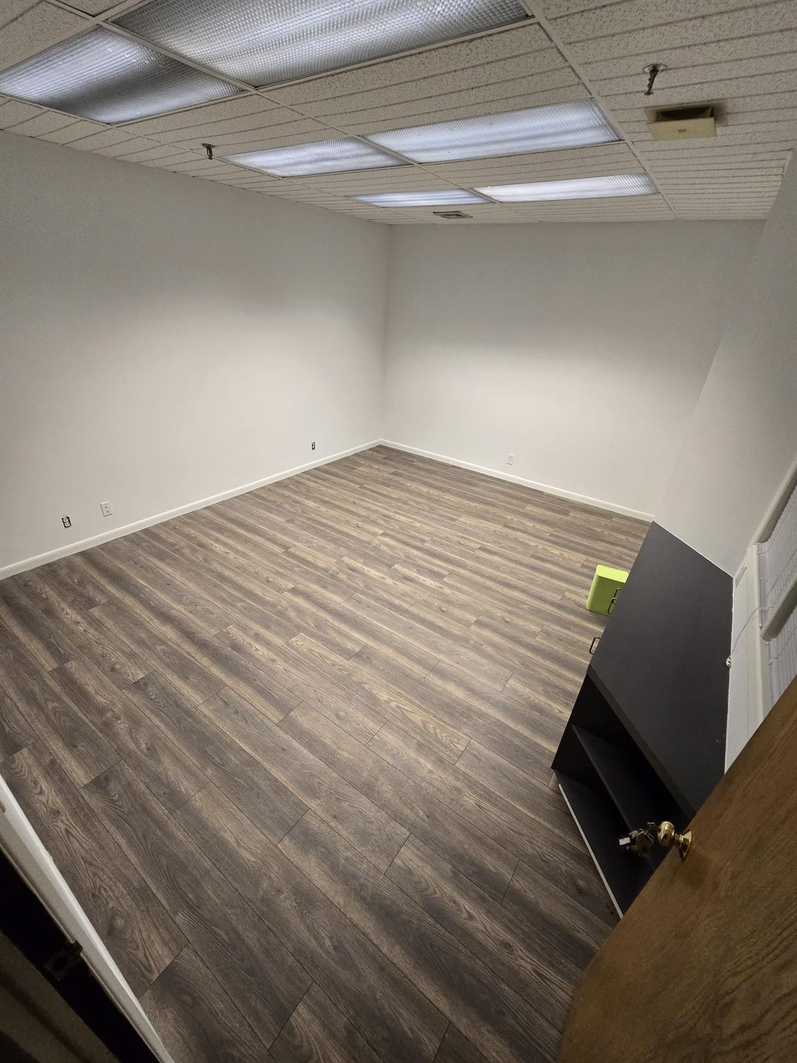 Basement with wood finished floors, a paneled ceiling, and baseboards