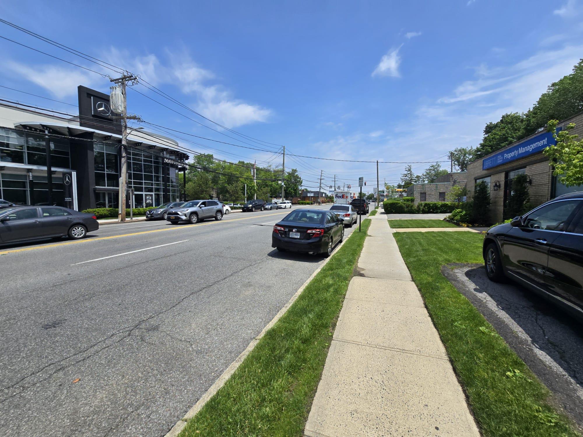 View of asphalt road with curbs and sidewalks