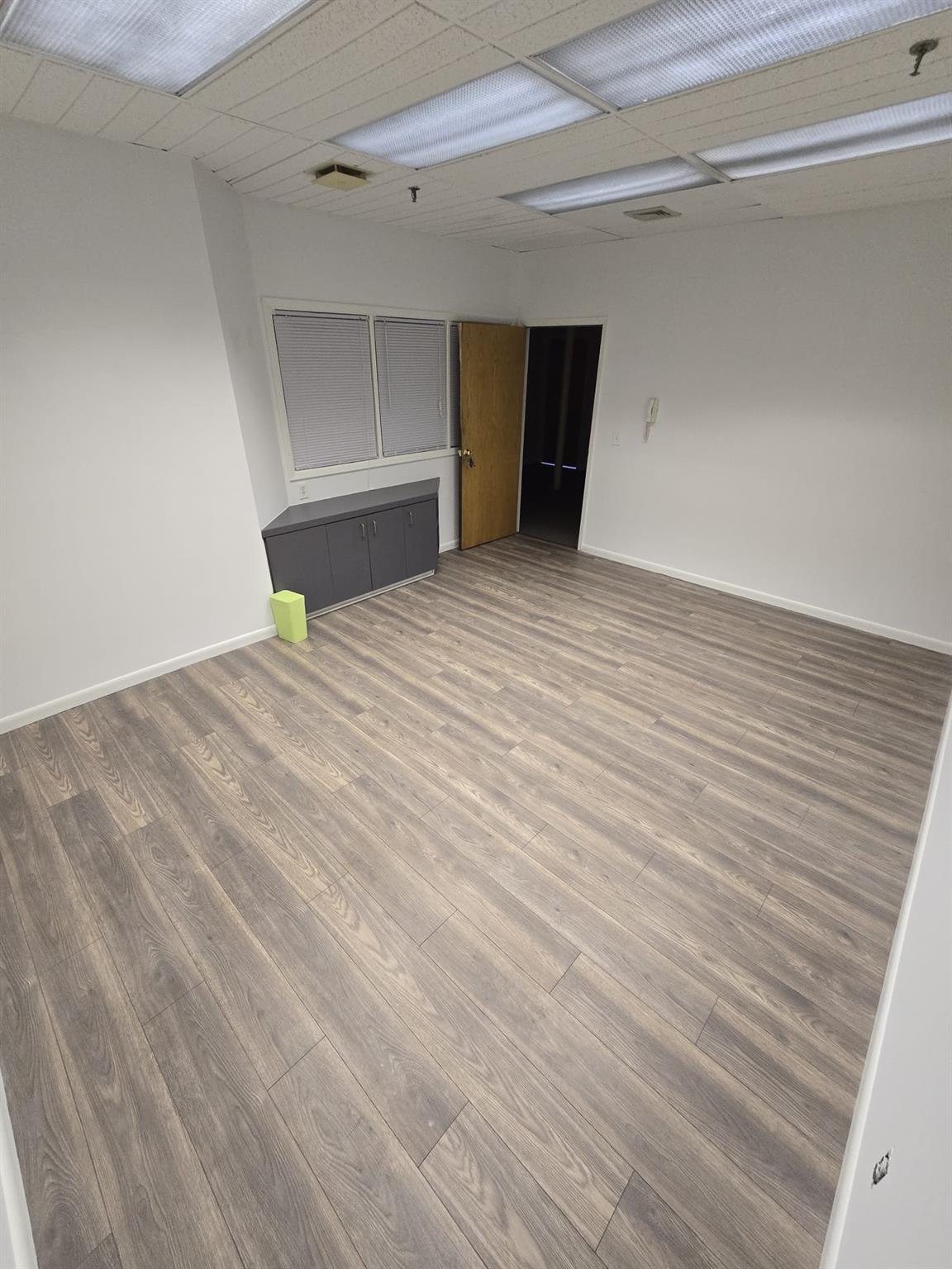 Unfurnished room with wood finished floors, baseboards, and fire sprinkler in ceiling