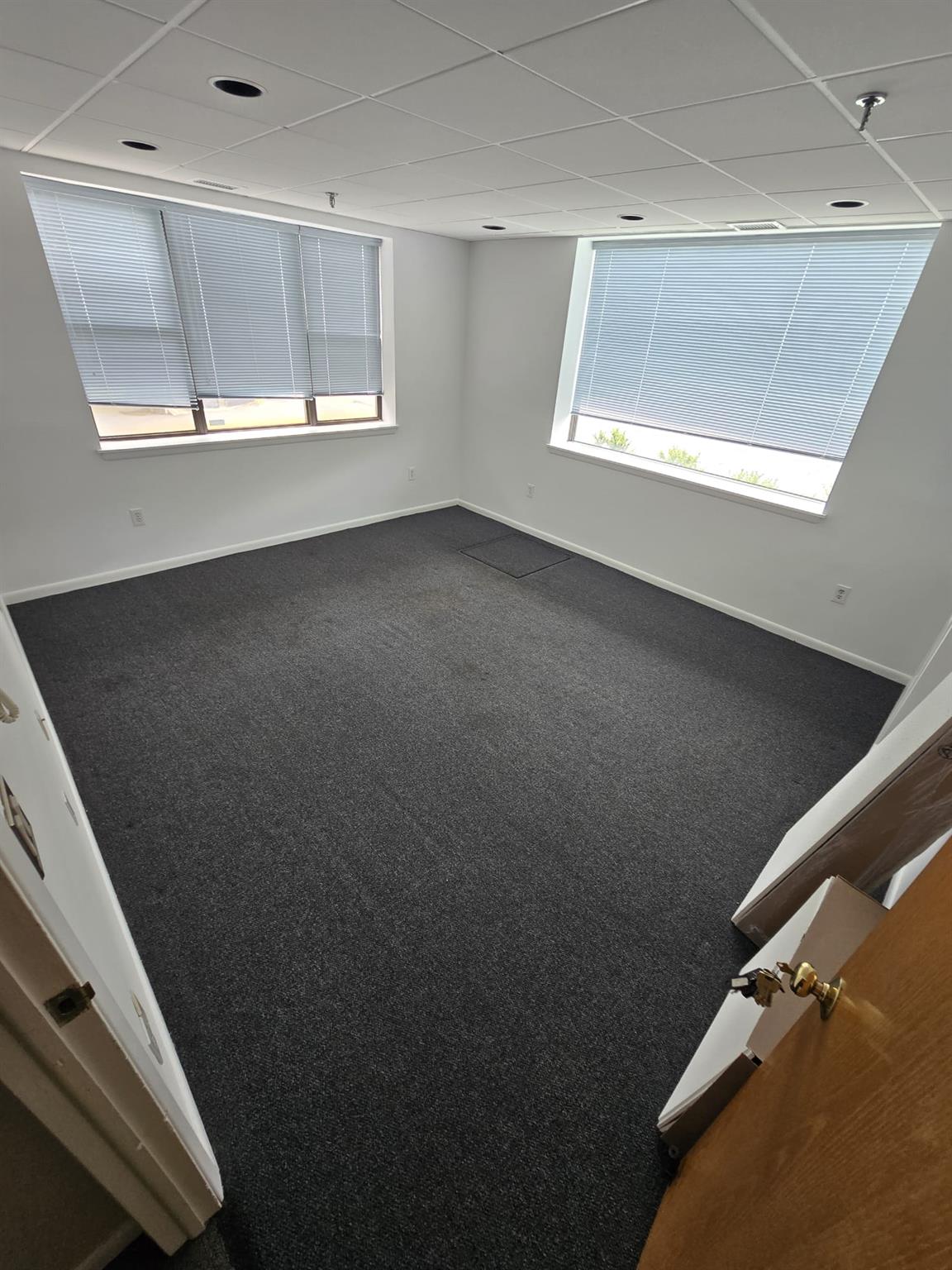 Spare room with dark carpet, baseboards, and a paneled ceiling