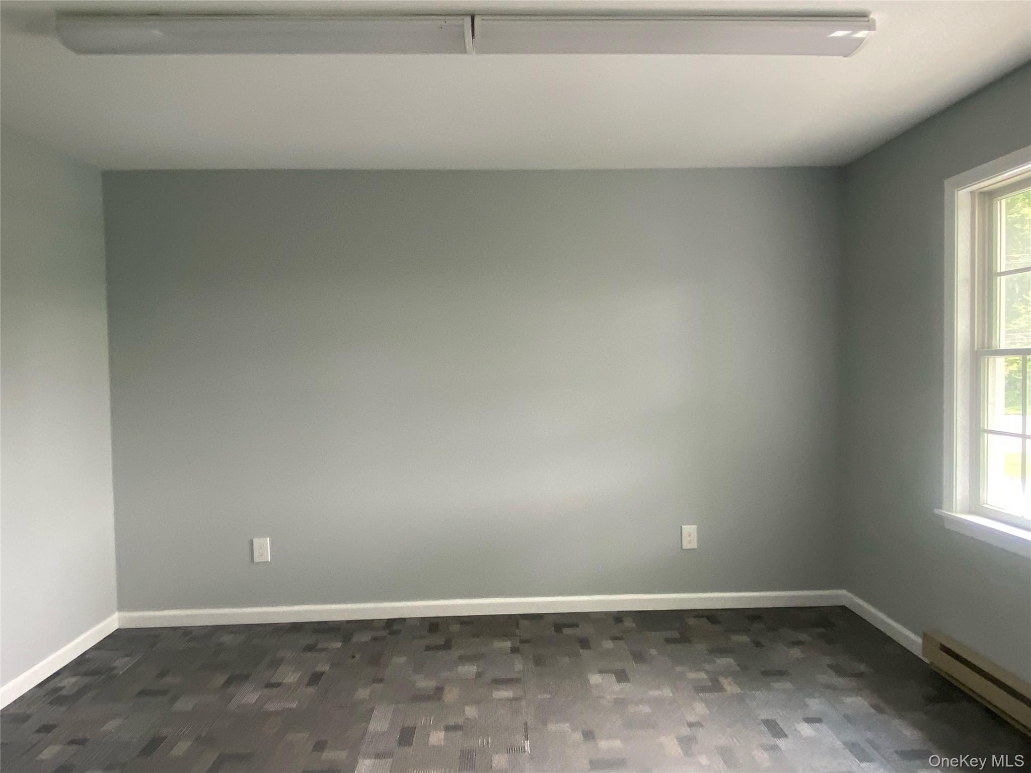 Empty room featuring a baseboard heating unit and dark wood-style floors