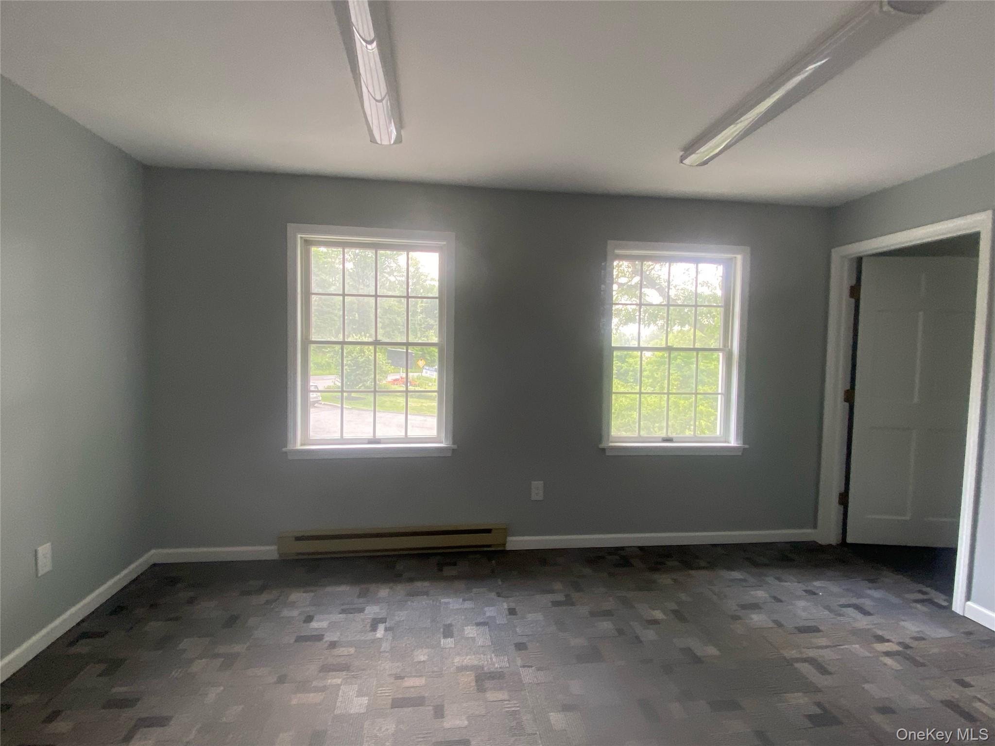 Unfurnished room with baseboard heating and baseboards