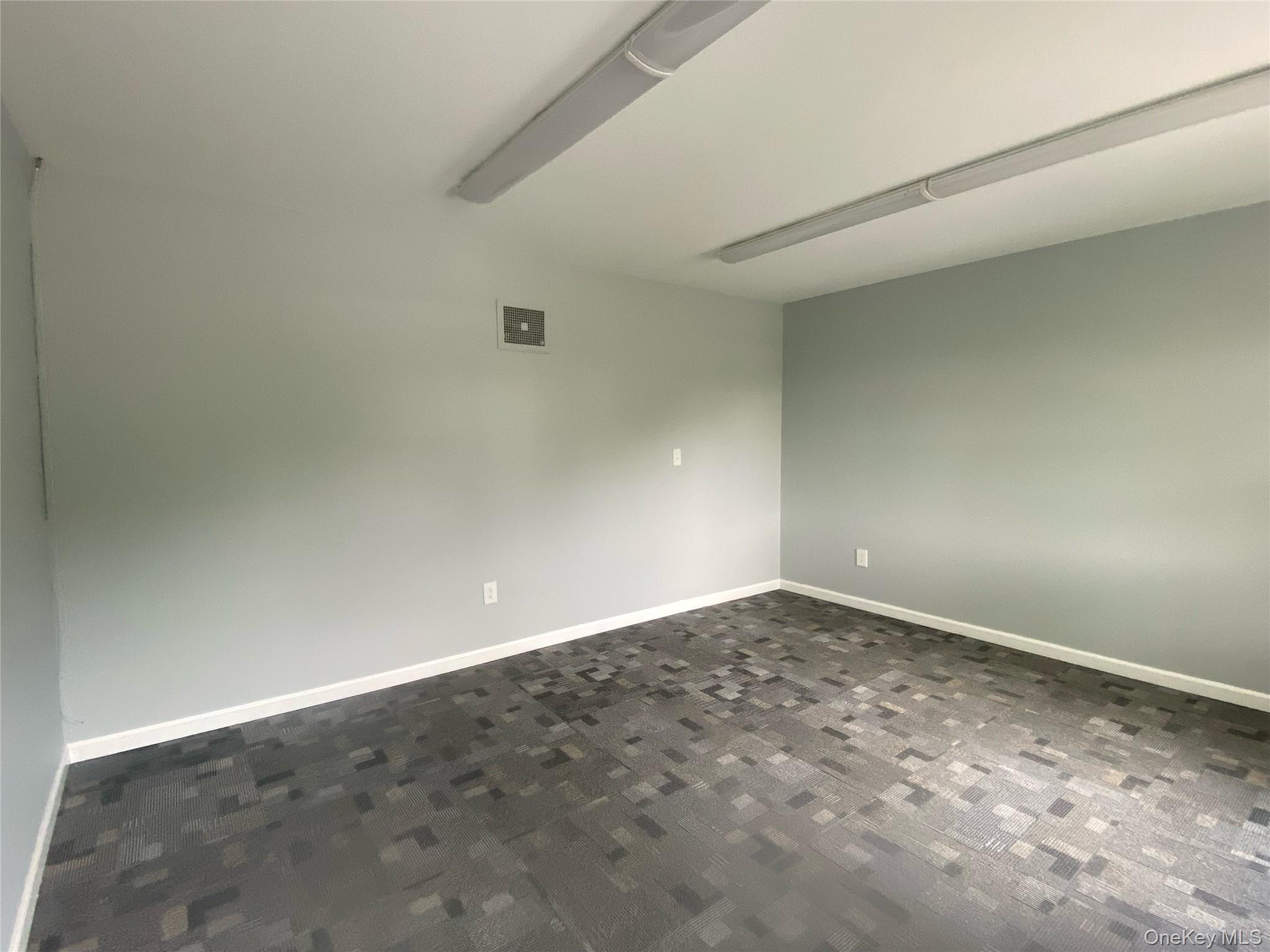 Empty room featuring baseboards and dark colored carpet