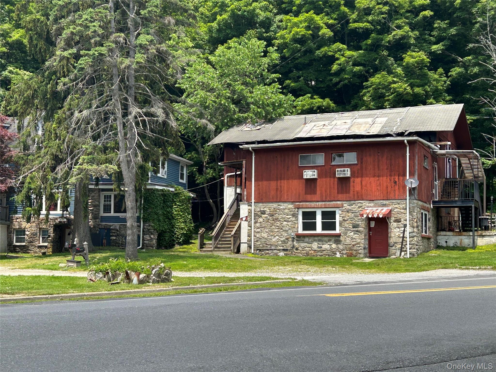 View of front facade featuring stone siding, stairs, and a wooded view