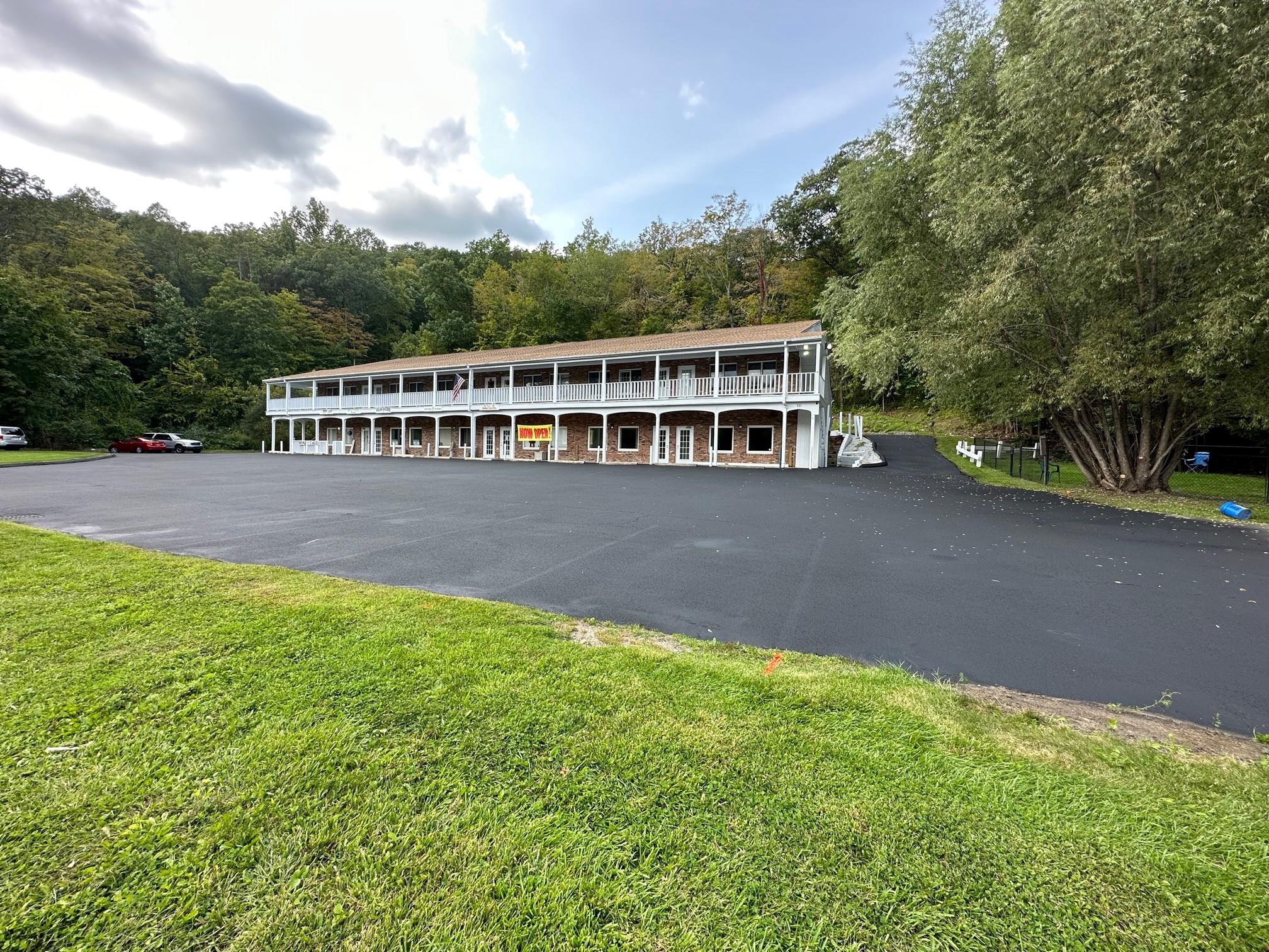 View of front of house featuring uncovered parking, a front lawn, and a forest view