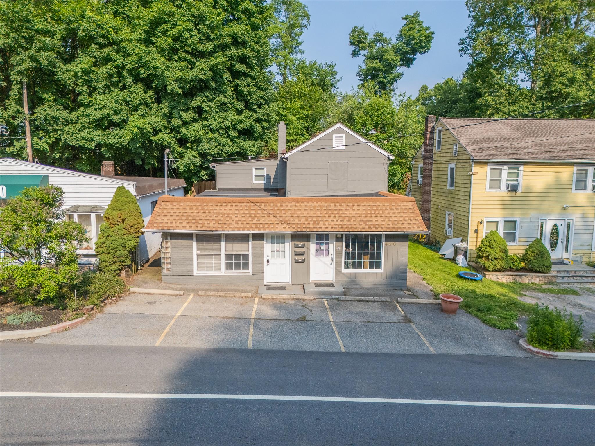 View of front of home featuring uncovered parking and view of wooded area