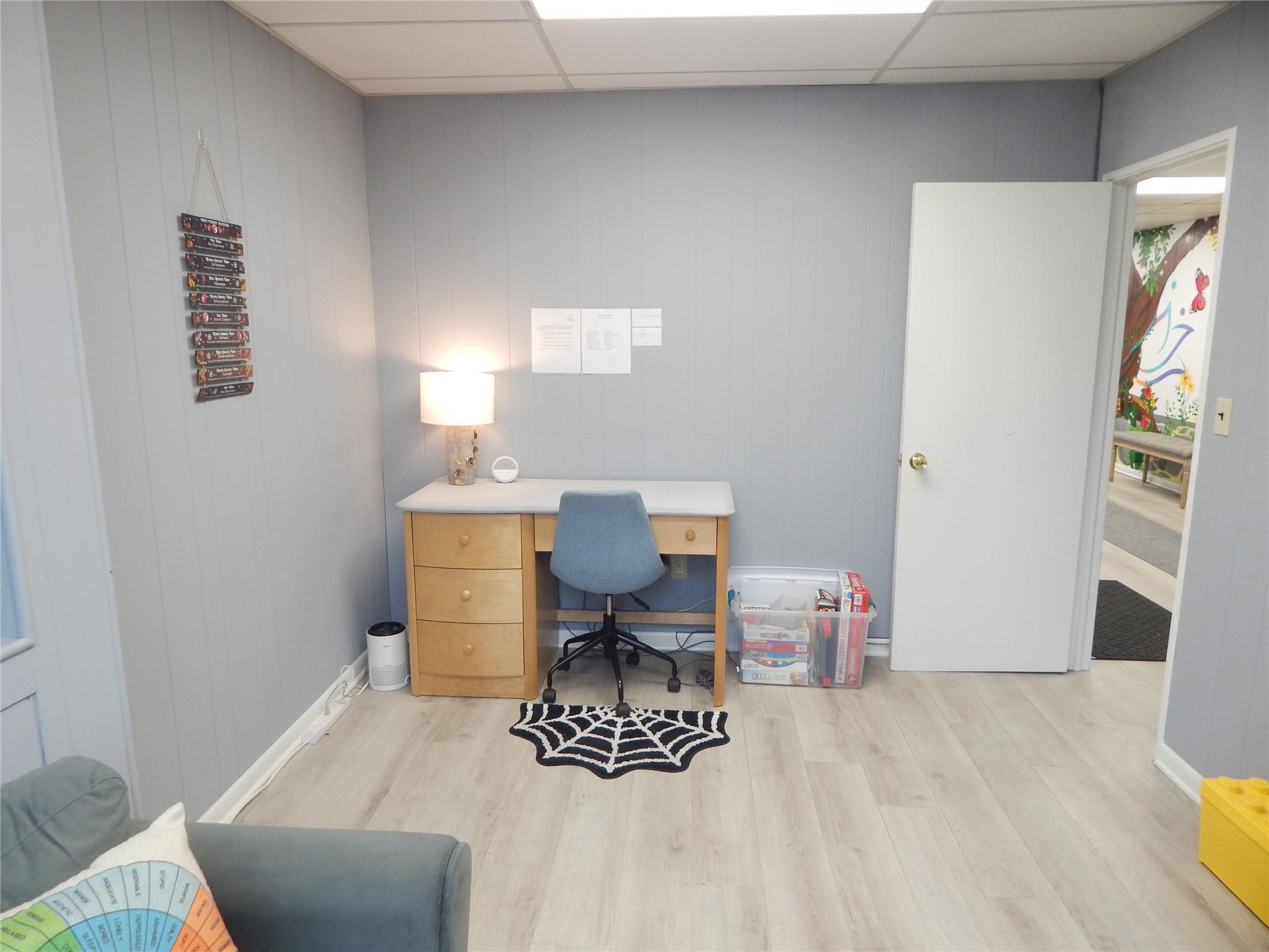 Office with a paneled ceiling and light hardwood / wood-style flooring