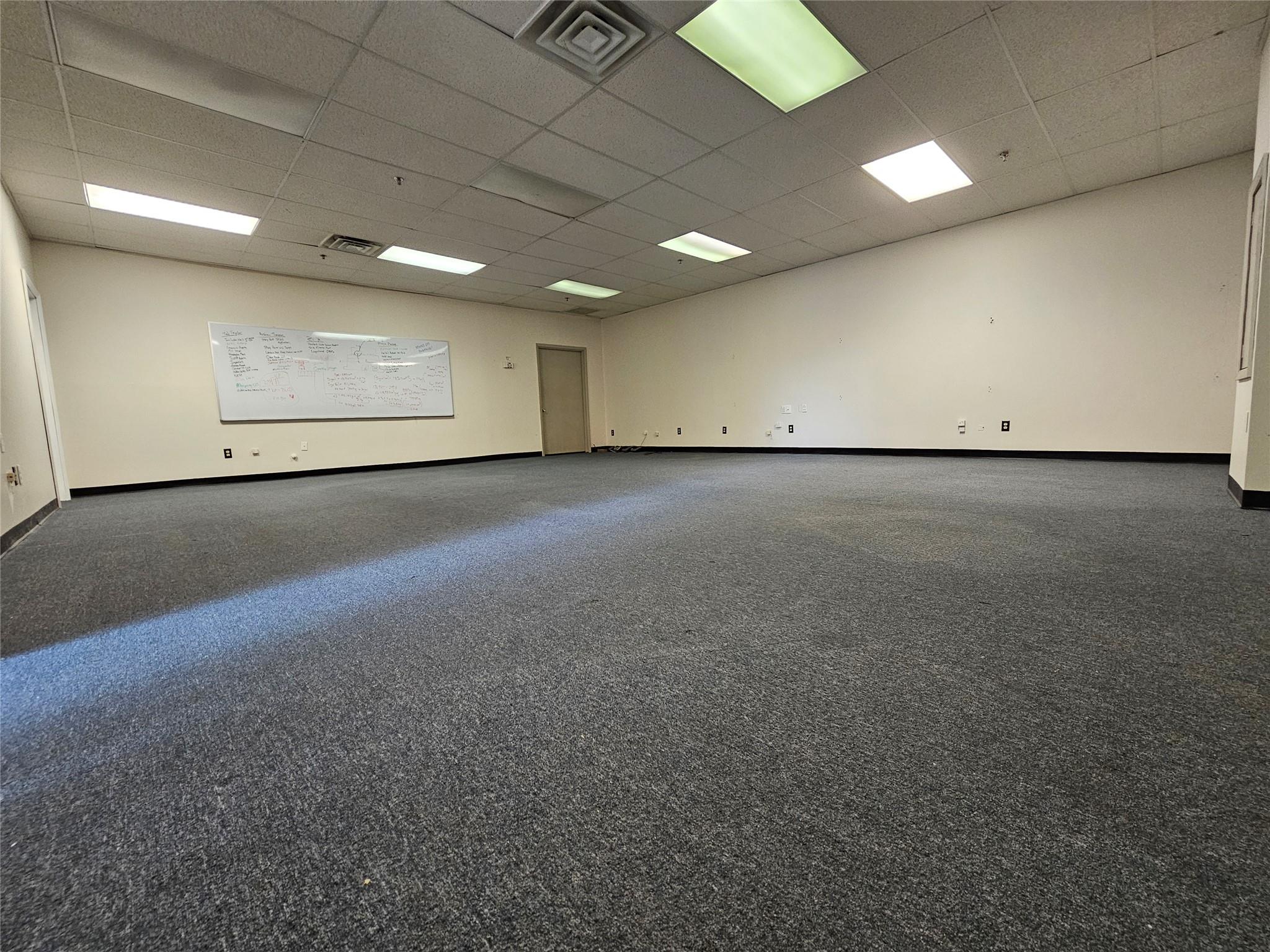 Carpeted spare room featuring a paneled ceiling and baseboards