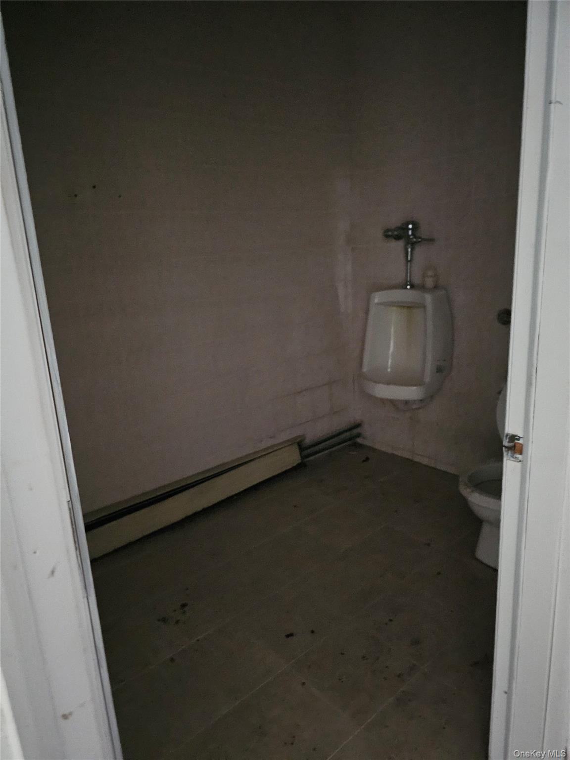Bathroom featuring baseboard heating, tile walls, and tile patterned floors