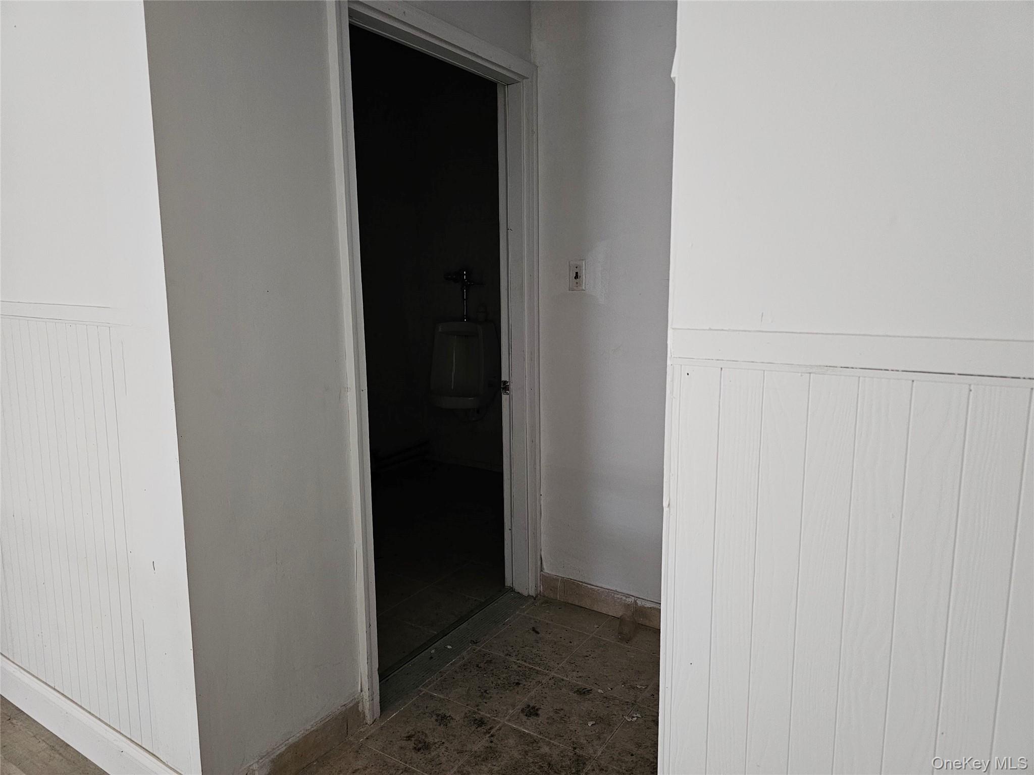 Corridor featuring a wainscoted wall and baseboards
